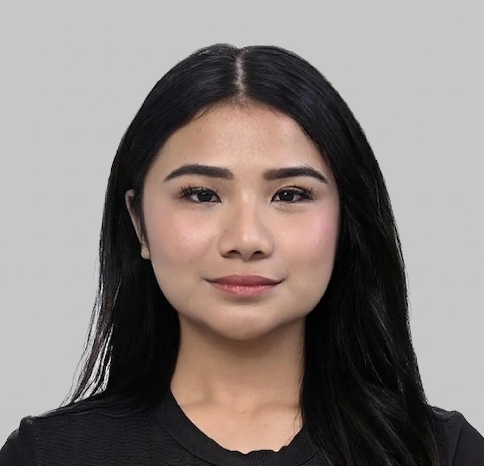 A portrait of a young woman with long black hair, wearing a black top, smiling slightly, against a plain gray background.
