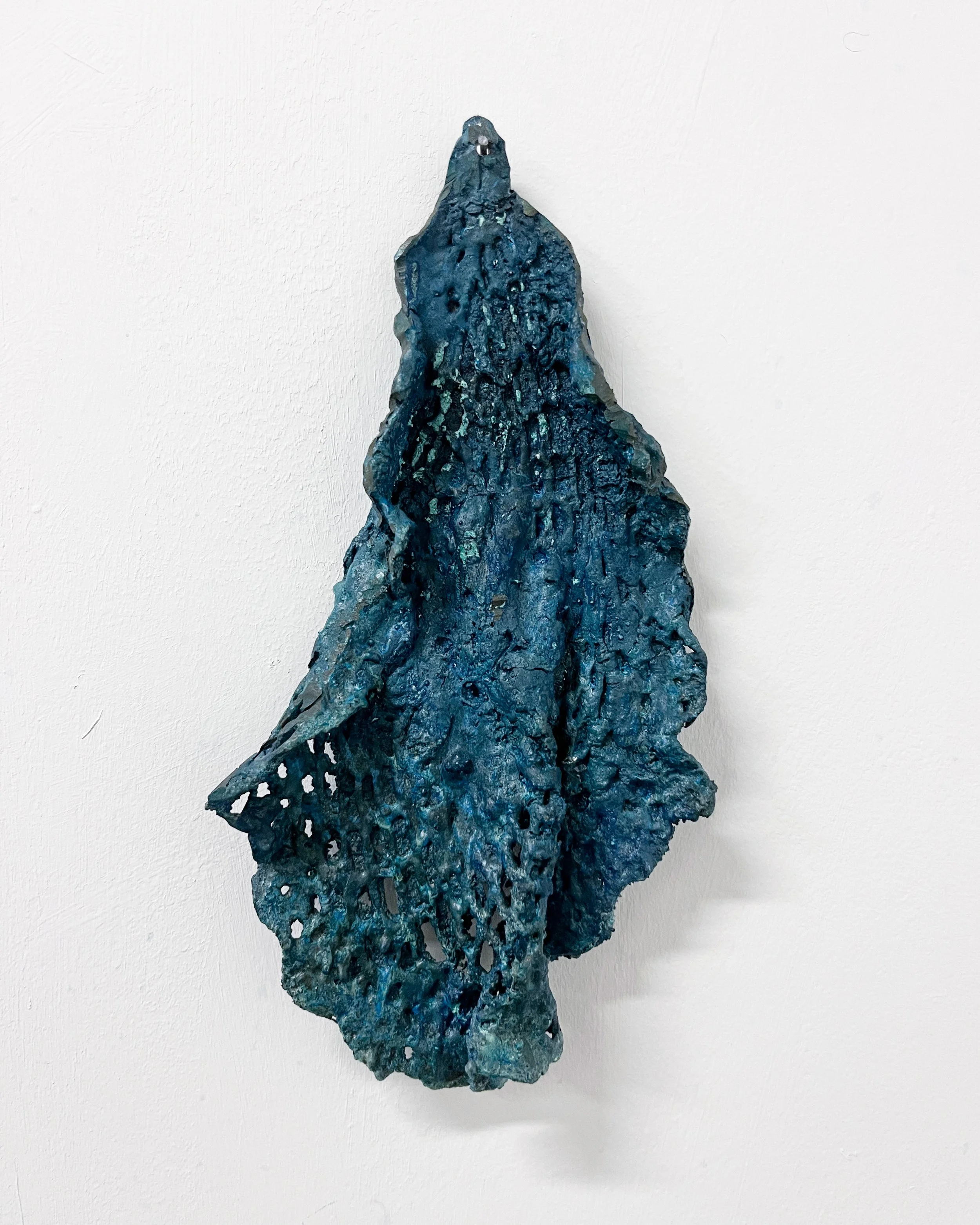 Abstract blue textured sculpture on a white wall.