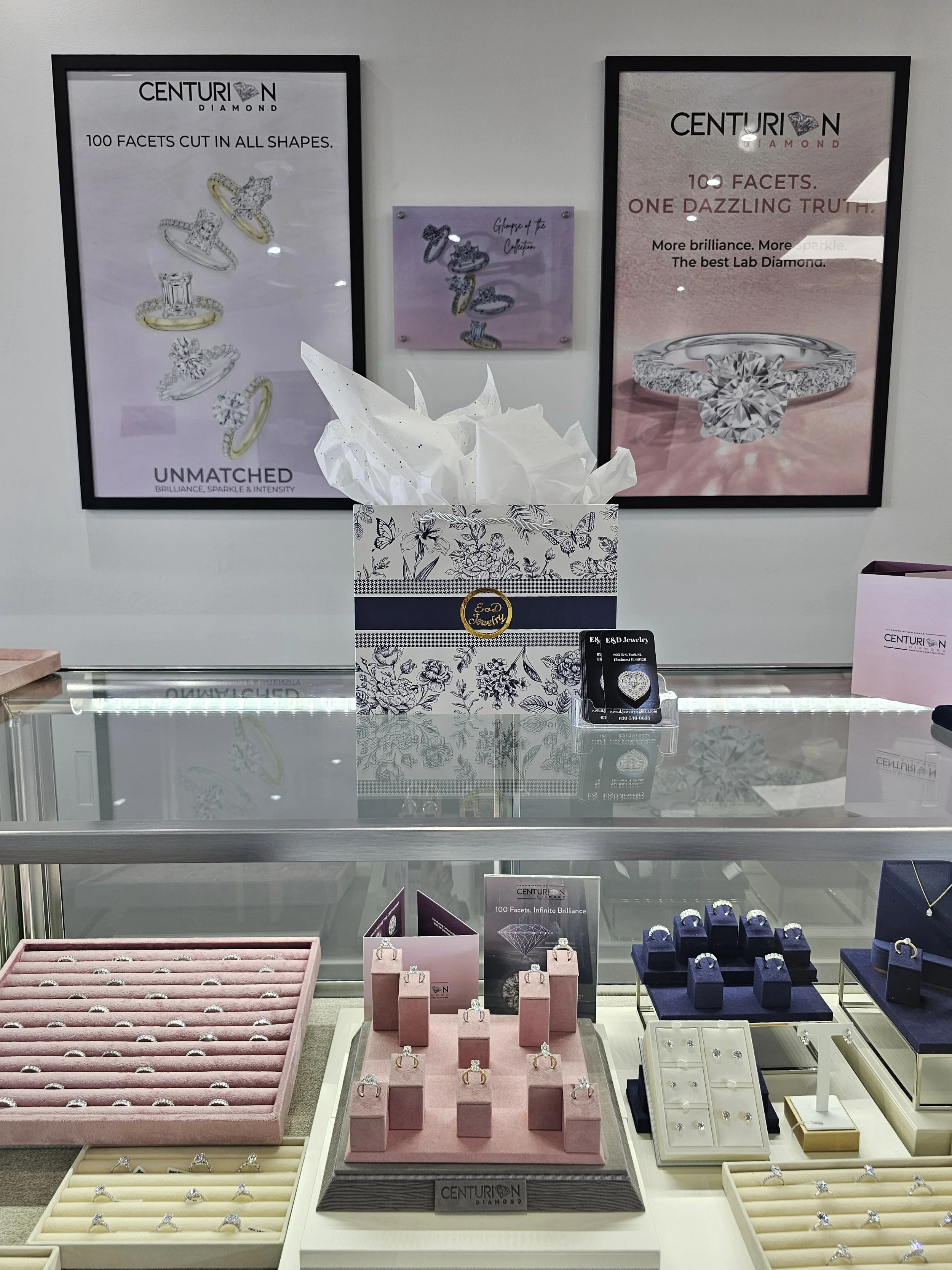 Display of various diamond rings and jewelry in a jewelry store, with promotional posters on the wall advertising Centurion Diamond's features.