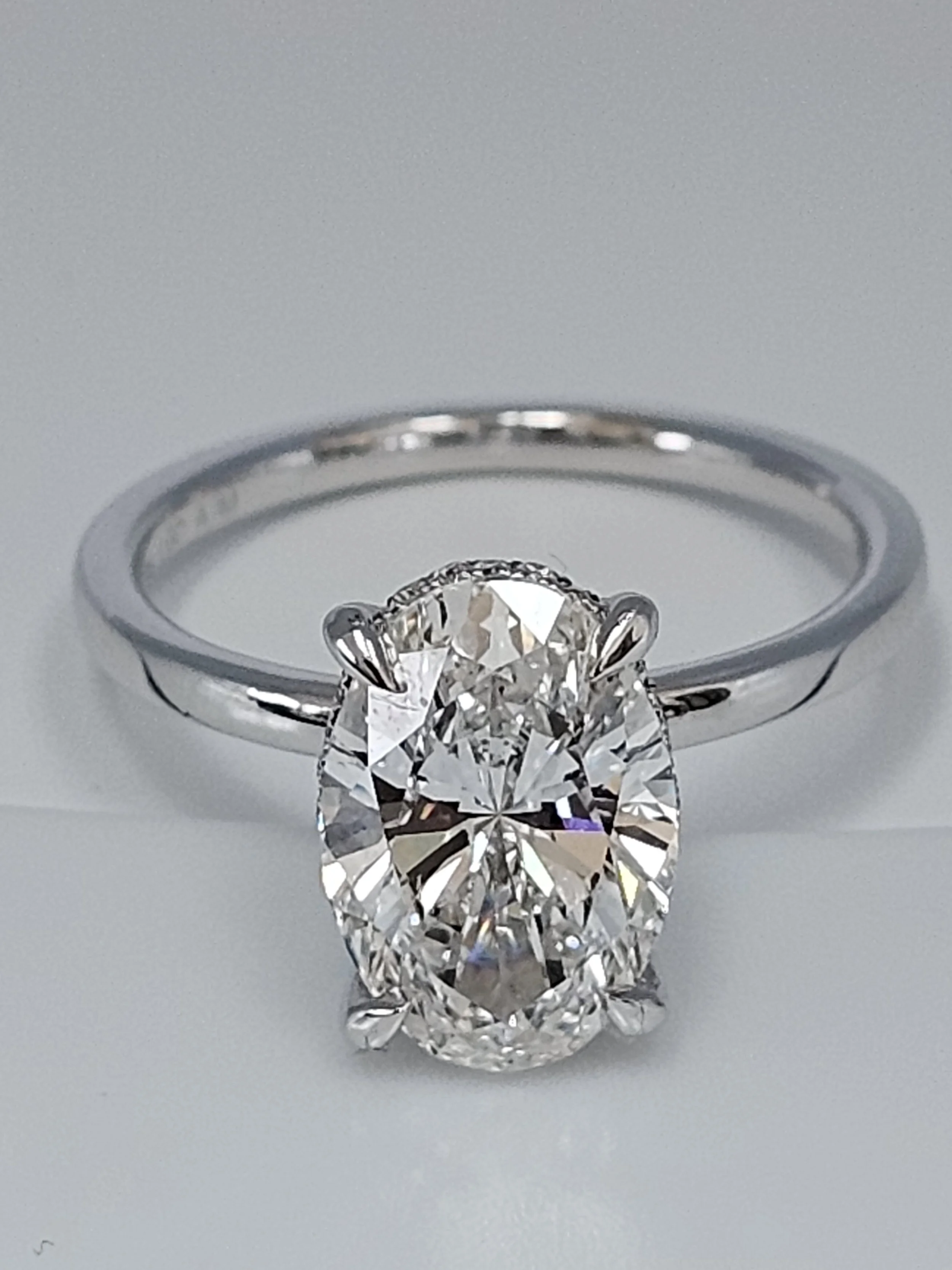 Close-up of a 14 kt white gold engagement ring with a 3 karat round diamond set in a silver band placed in a jewelry display setting.
