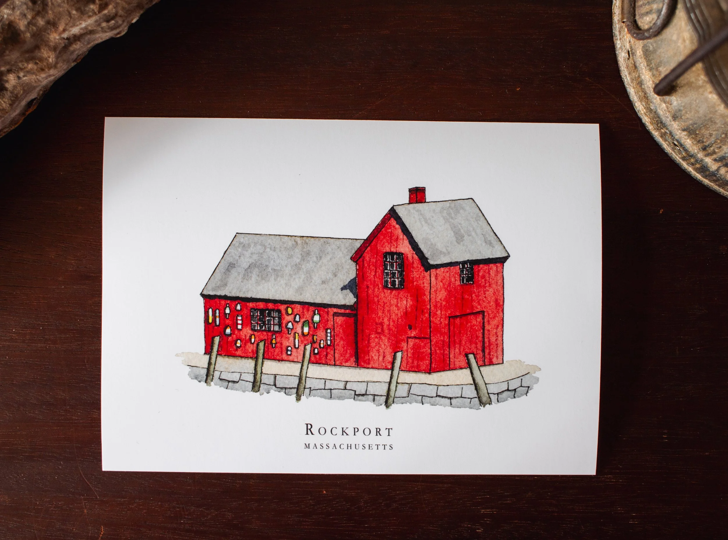 Illustration of a red house with a gray roof, set against a white background. The house has multiple windows and a small chimney. The illustration is under the text "Rockport Massachusetts".