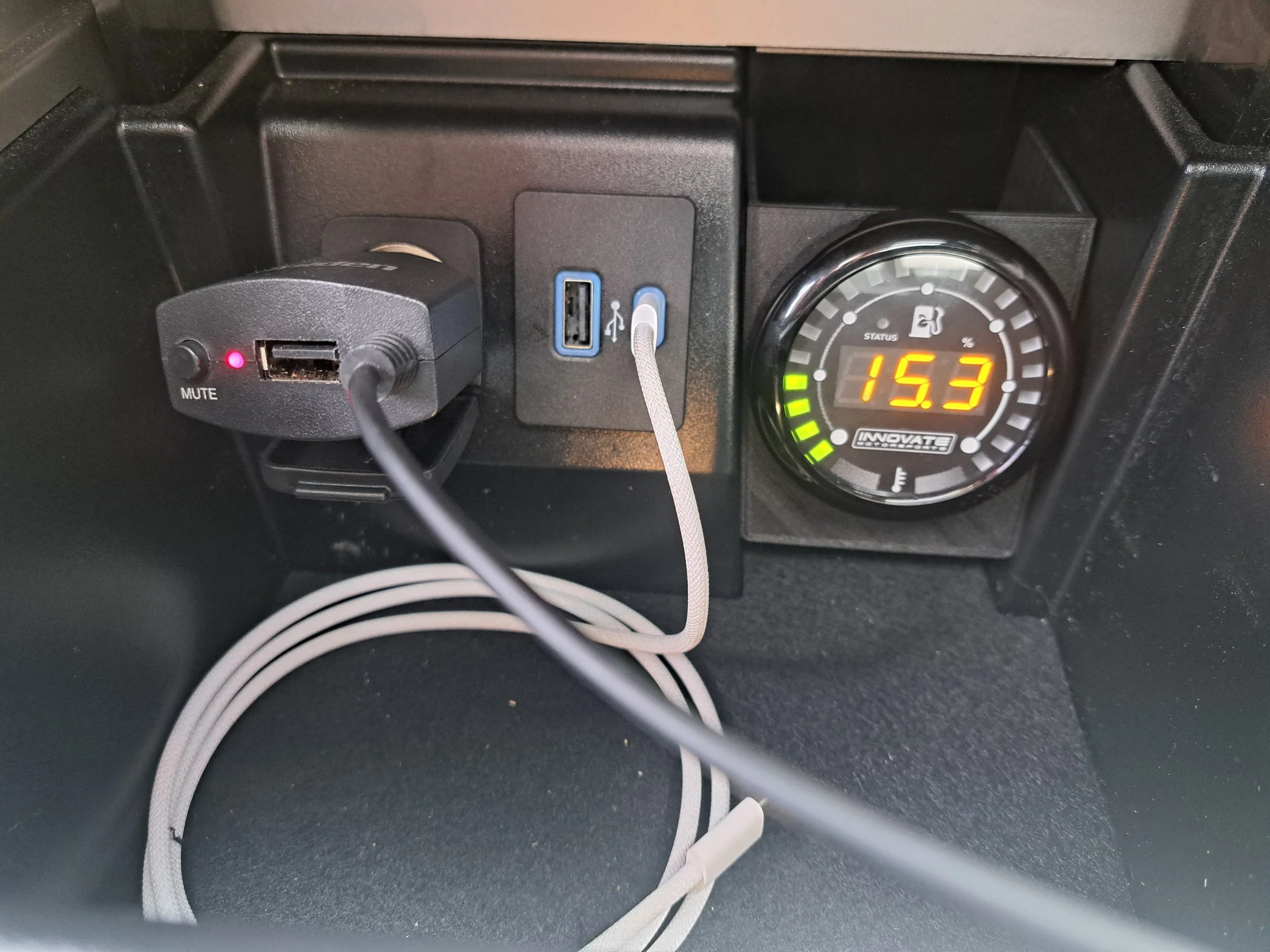 Inside a vehicle dashboard, showing a mounted USB charger with a power indicator, a USB port, and a power socket, along with a digital gauge displaying the number 15.3 and a series of green indicator lights. Ethanol sensor content gauge for Explorer