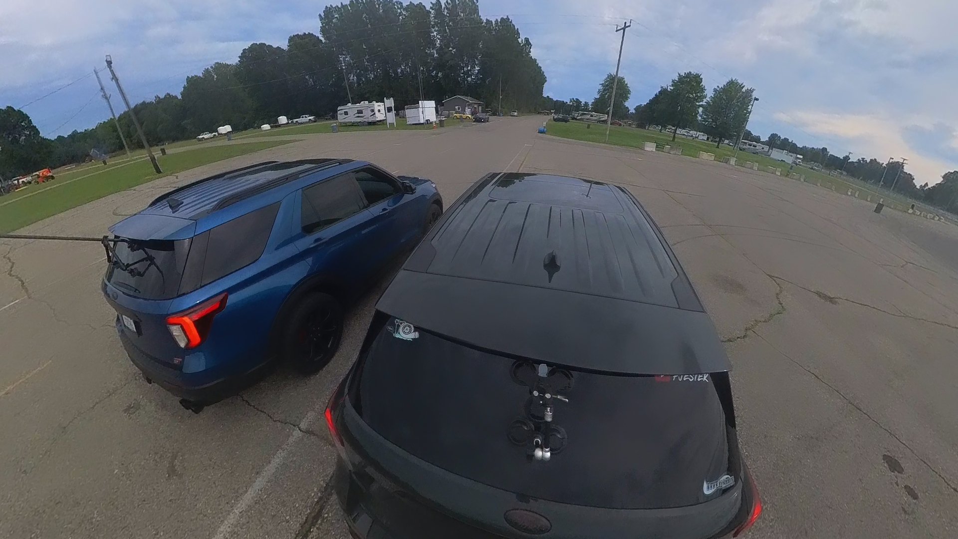 Two Explorer STs lining up to race, one blue and one black, and a few trailers and buildings in the background.