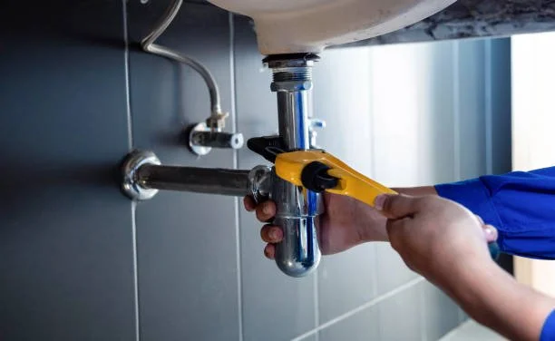Person using a wrench to tighten a pipe under a sink.