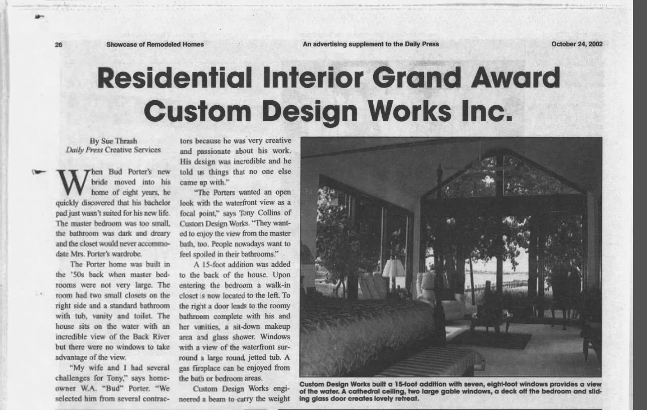 A black-and-white newspaper page featuring an article titled "Residential Interior Grand Award Custom Design Works Inc." with a photograph of a screened-in porch with large windows, chairs, trees, and a water body visible through the windows.