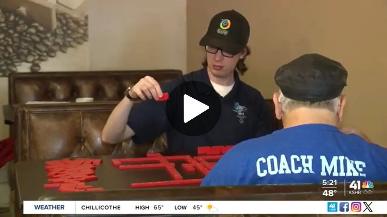 Screengrab of news video of two men at table in Kansas City playing dominos.