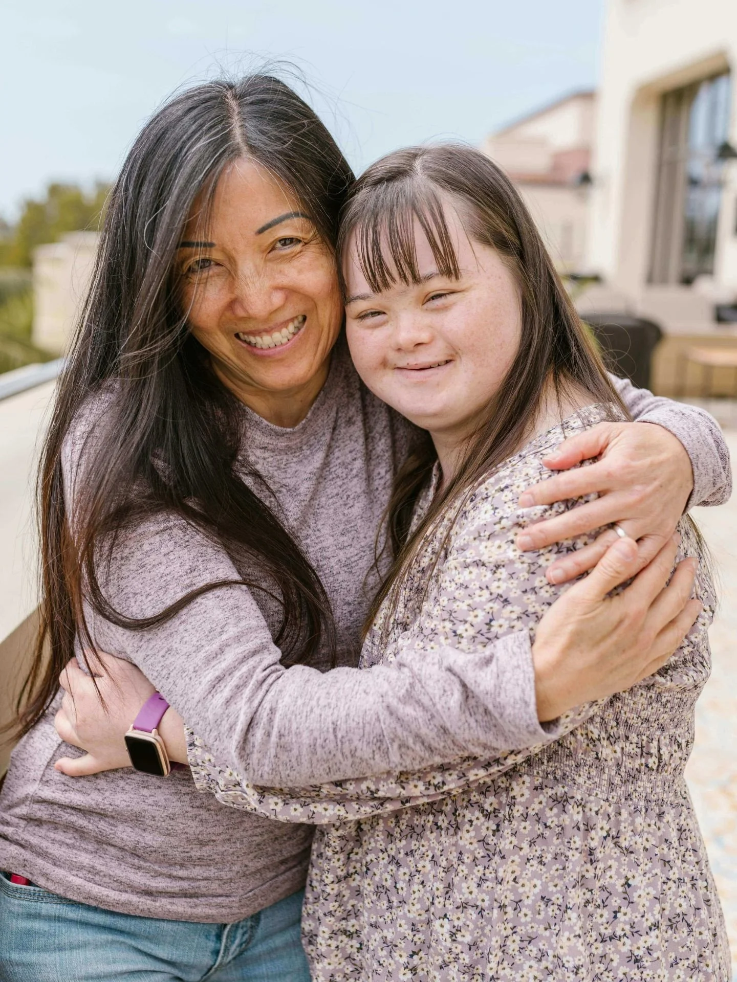 Smiling mother hugging smiling daughter with Down syndrome outside in Kansas.