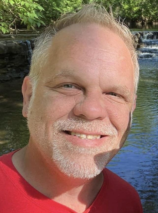 Dominick business director of The Dream Works smiling by stream.