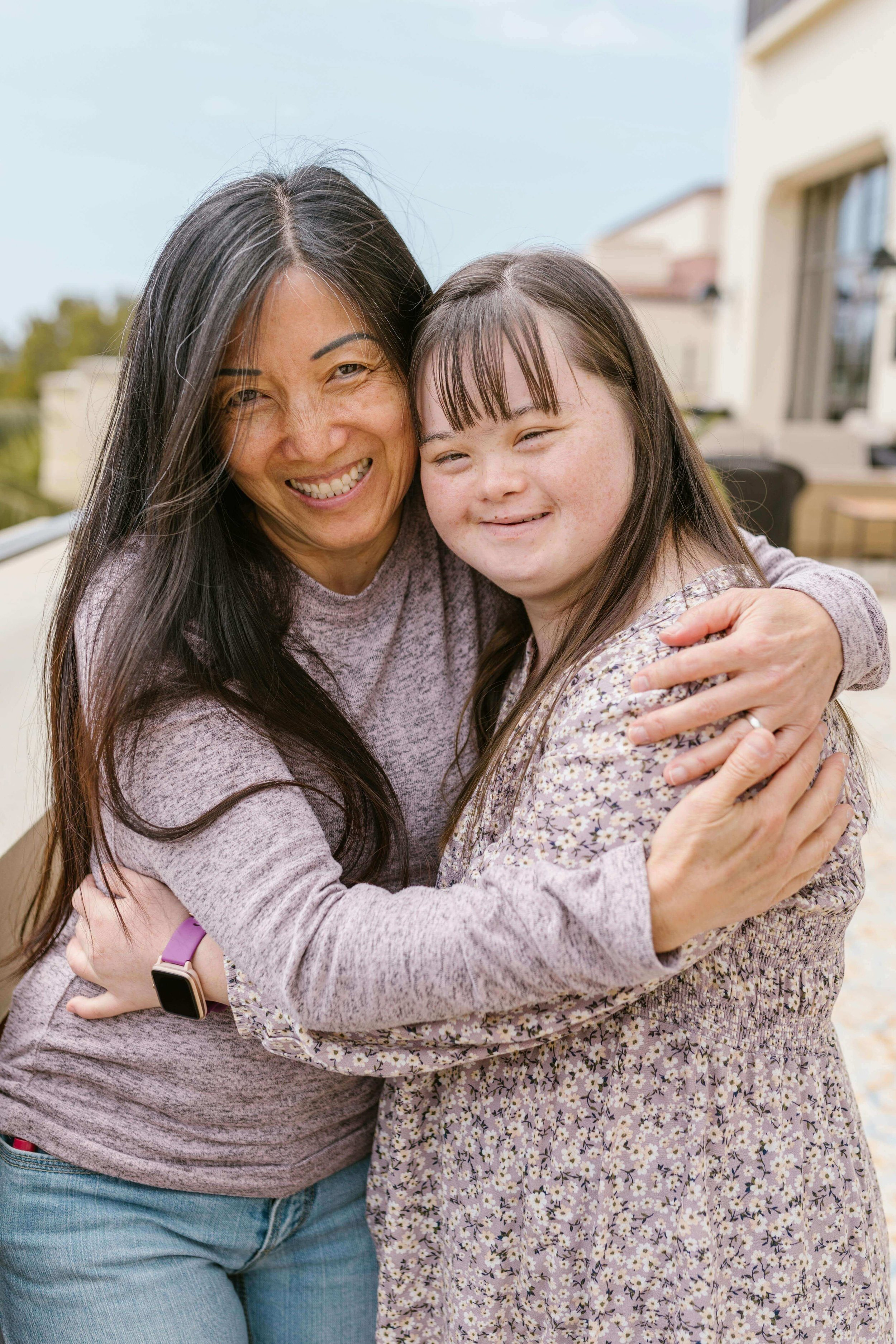 Smiling mother hugging smiling daughter with Down syndrome outside in Kansas.