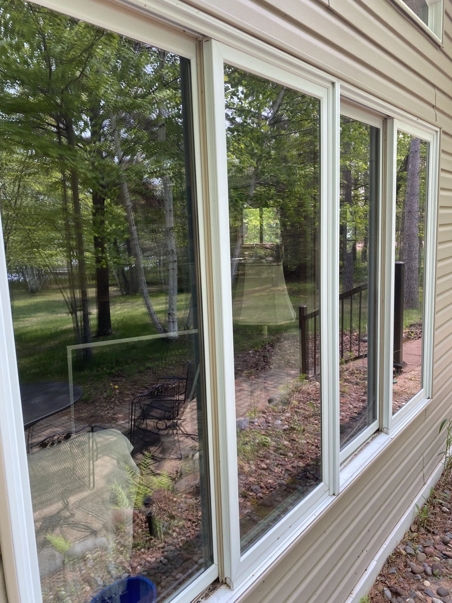 A modern backyard with a swimming pool, lounge chairs, and a patio area with outdoor furniture, surrounded by desert plants and trees.