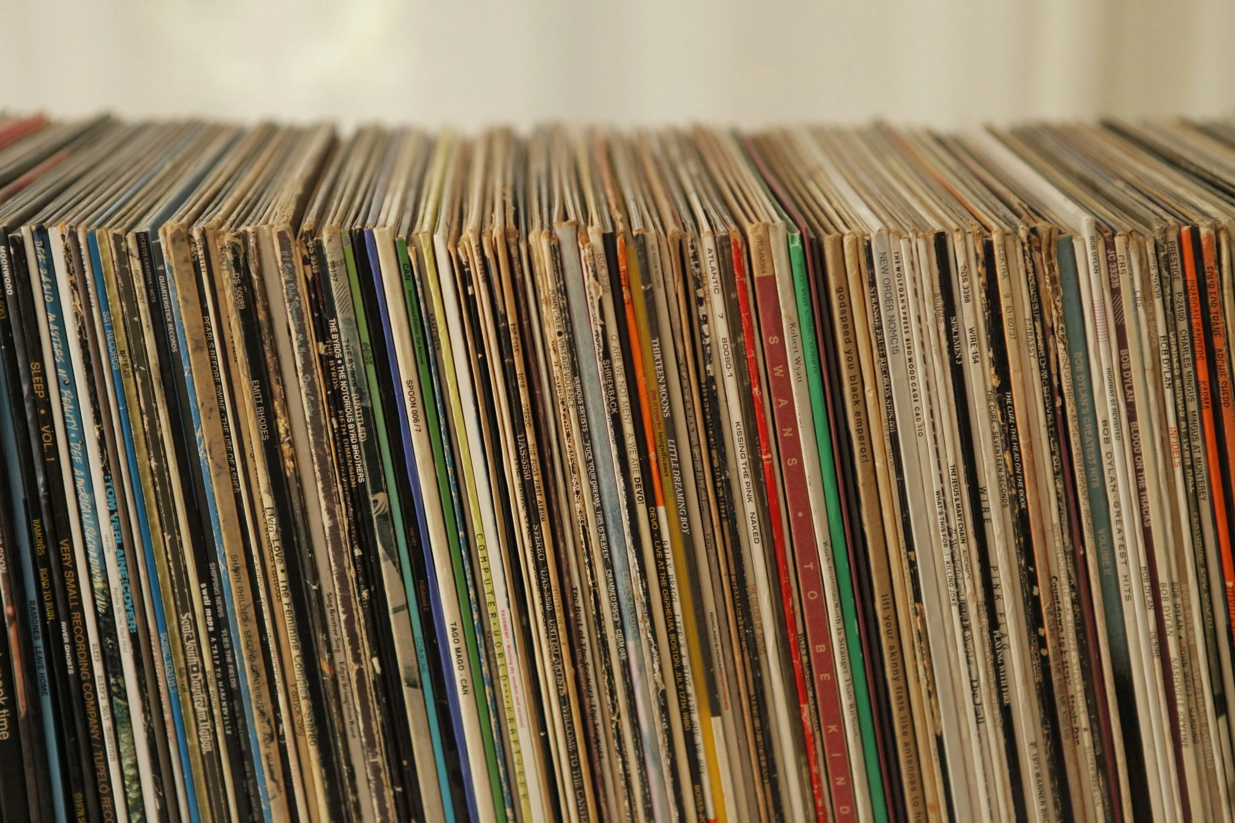 A close-up of a shelf filled with rows of vinyl records with colorful covers.