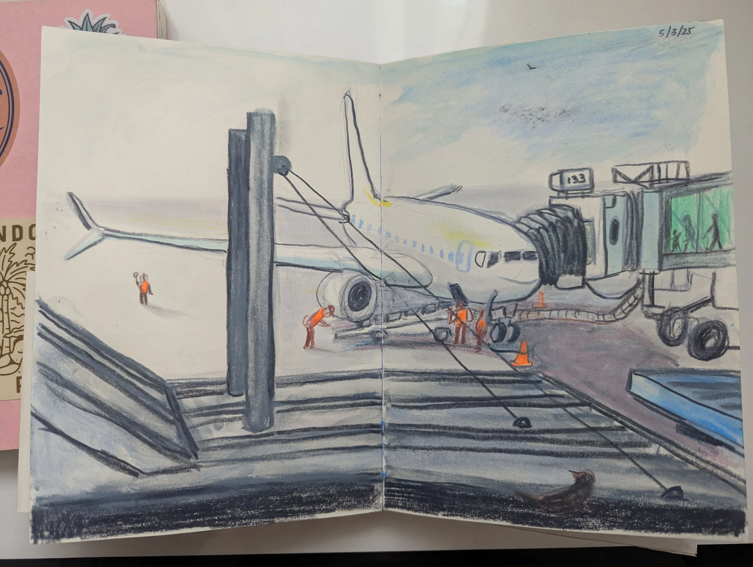 A drawing of a plane at an airport gate connected to a jet bridge, with workers in orange safety vests around it, and some transportation cones. The scene is sketched with colored pencils, with a light sky sky in the background, and date '5/3/25' wri