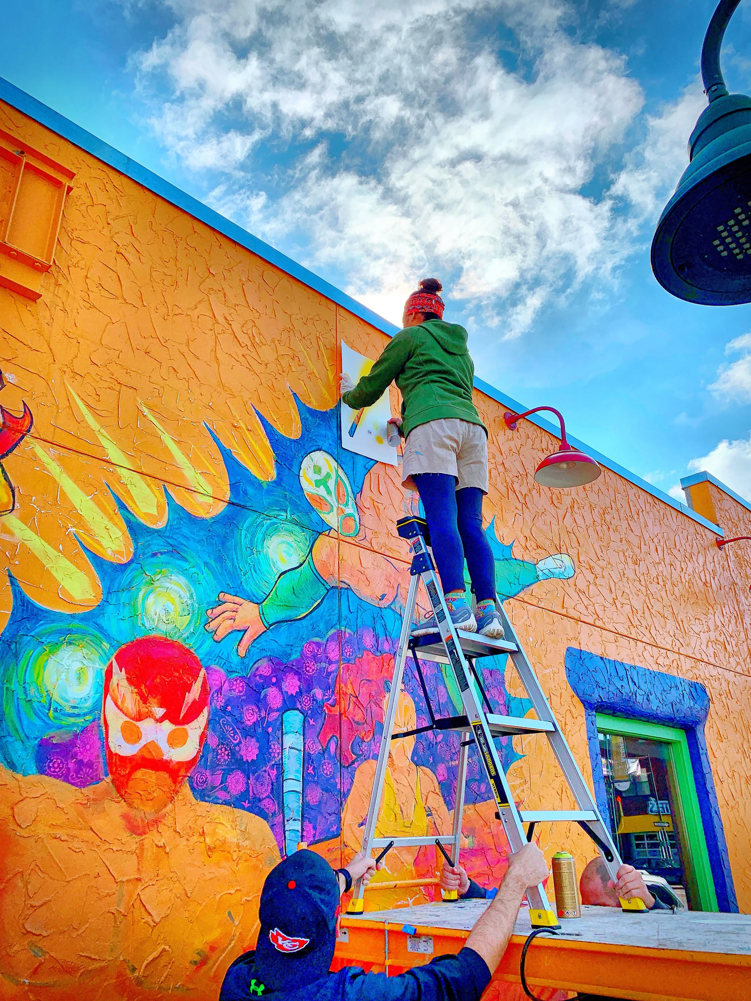 Phyllis J Garibay-Coon painting a mural at Taco Lucha in Manhattan, KS.