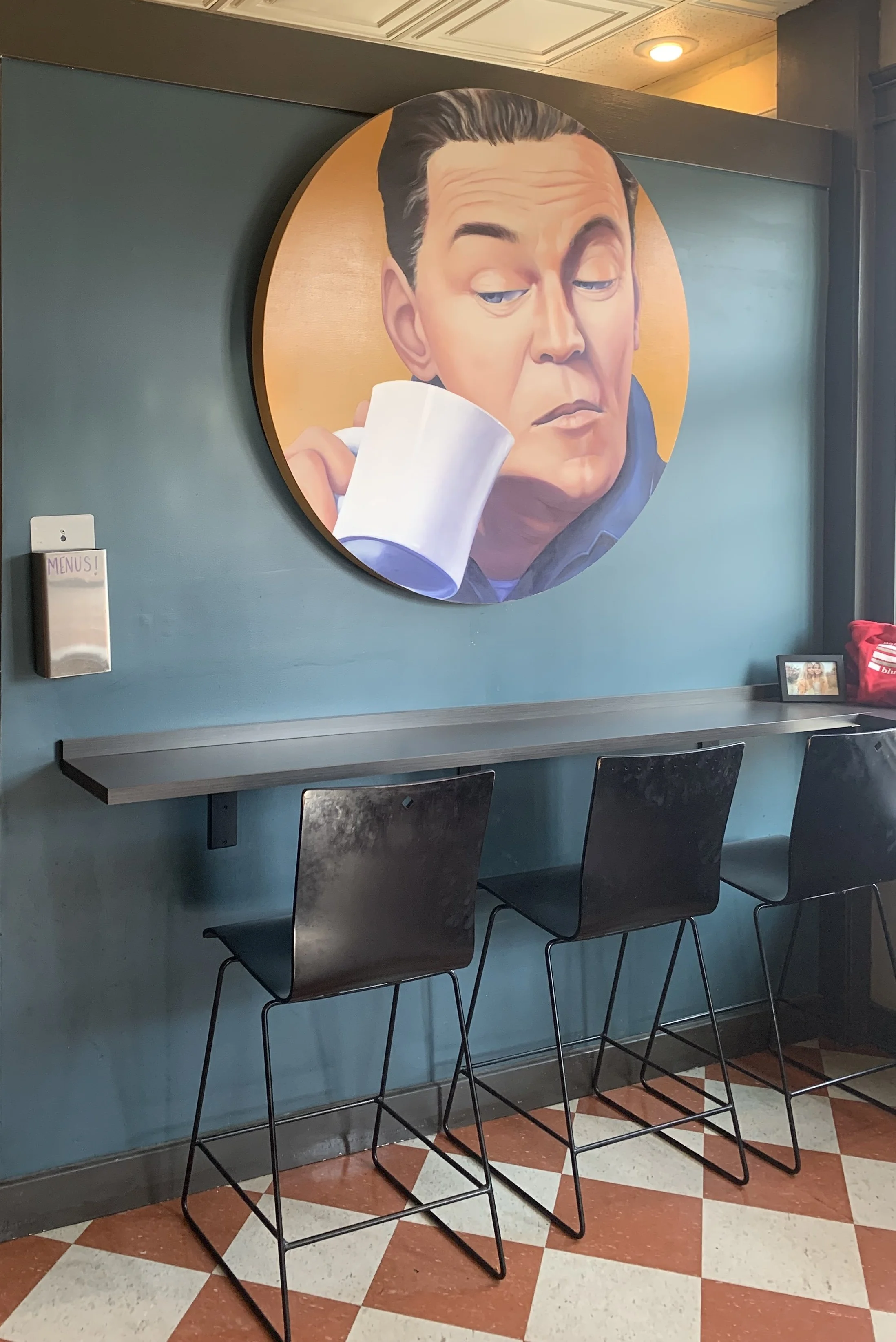 Decorative wall art featuring a circular portrait of a man enjoying a cup of coffee at Bluestem Bistro in Manhattan, KS.