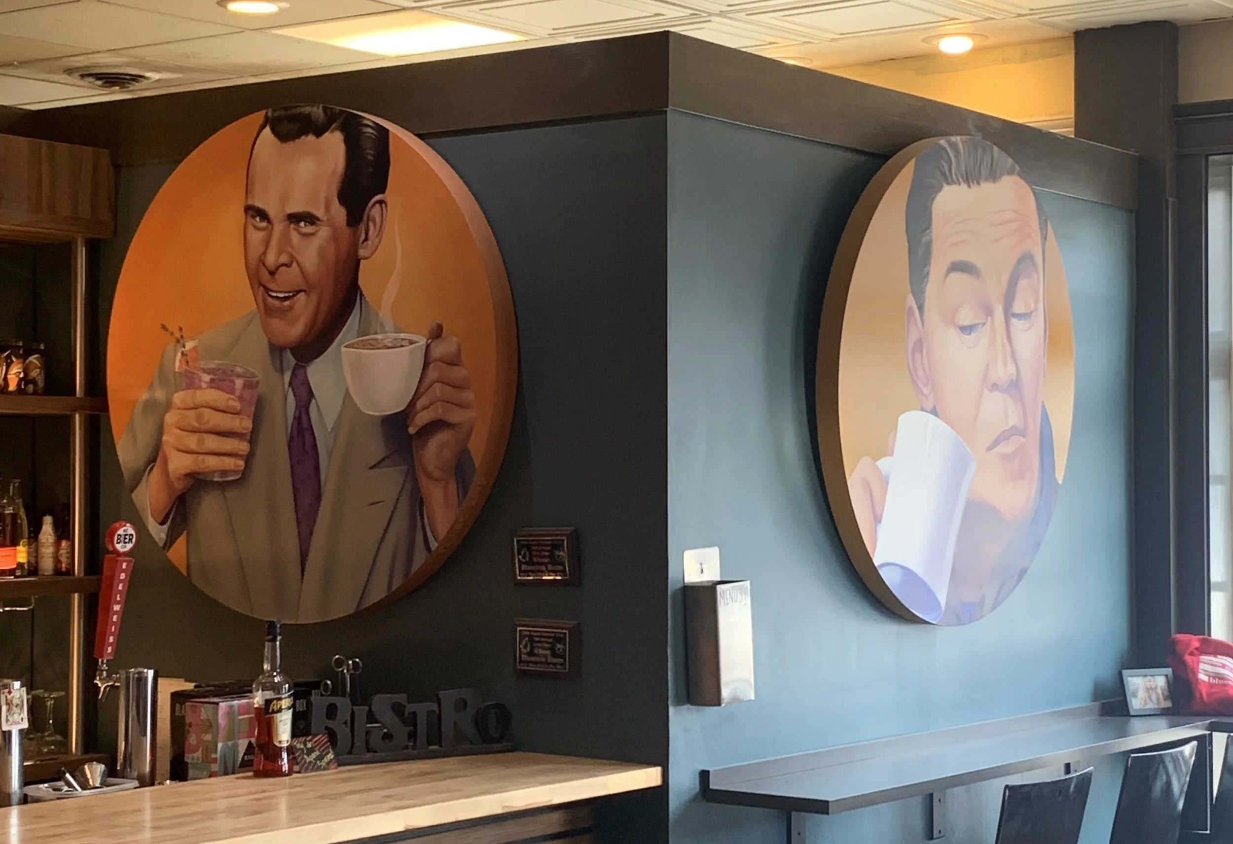 Decorative wall art featuring two circular portraits of men enjoying beverages at Bluestem Bistro in Manhattan, KS.