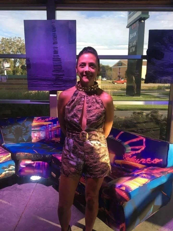 Artist Phyllis J Garibay-Coon with some of her pieces at a gallery show. 