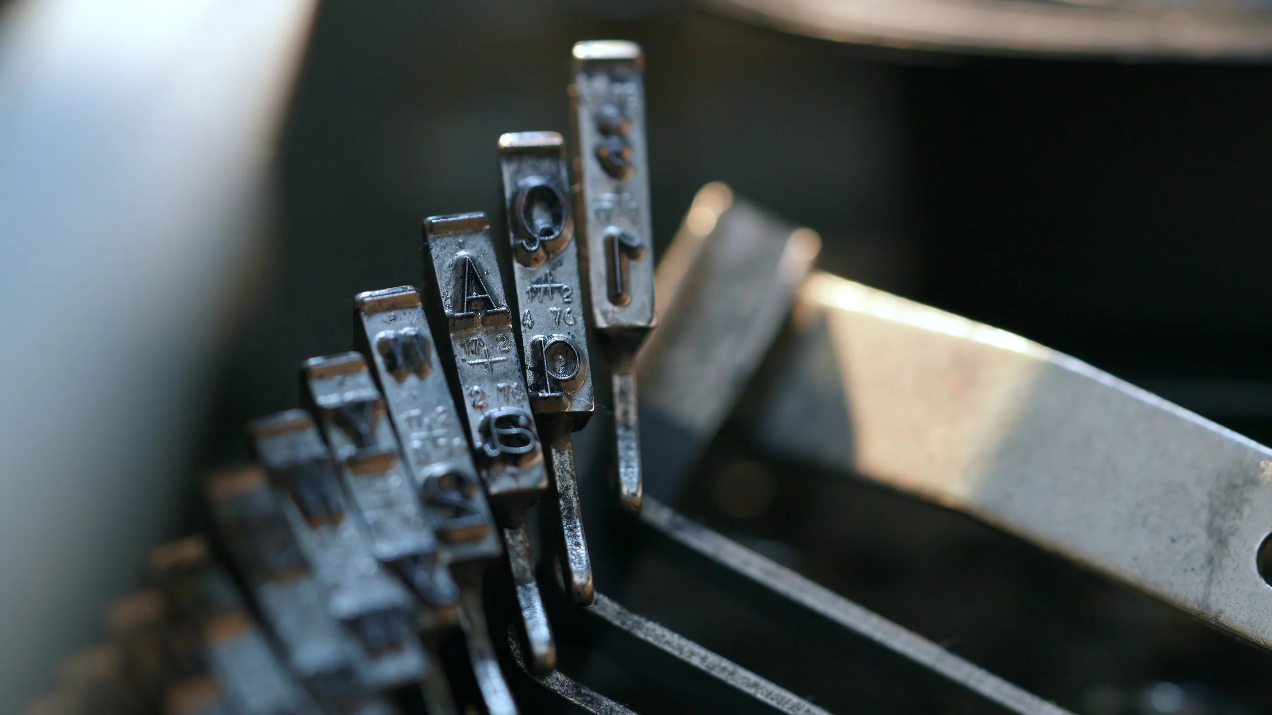 Close-up of mechanical typewriter keys with metal levers and embossed letters, showing part of the keyboard.