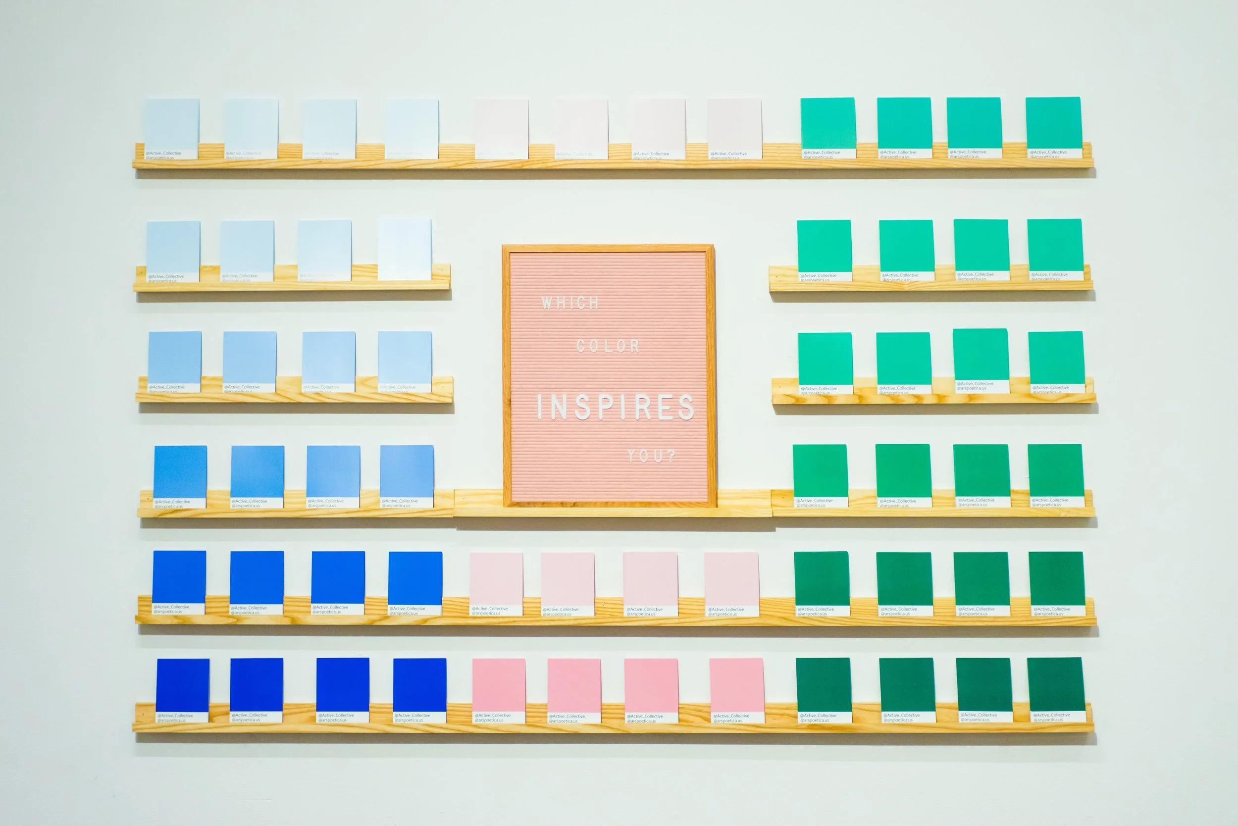 Color swatches arranged on wooden shelves with a pink felt letter board in the center that reads "WHICH COLOR INSPIRES YOU?".