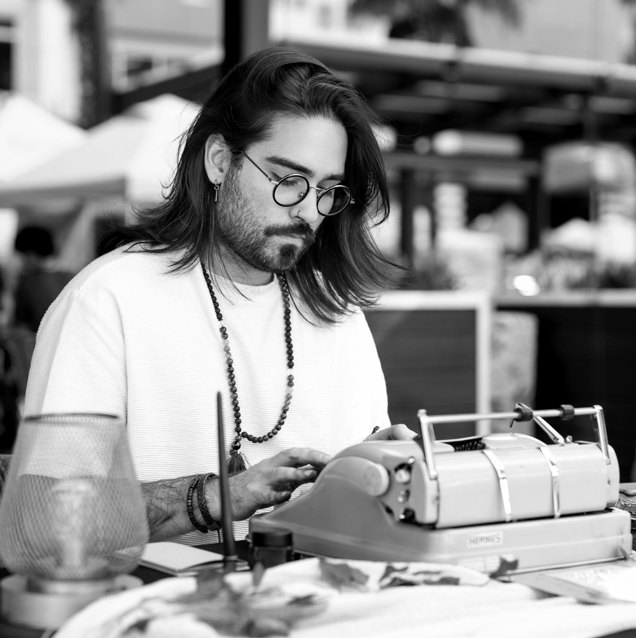 A man with long hair, glasses, and earrings is working with audio equipment in a professional setting.