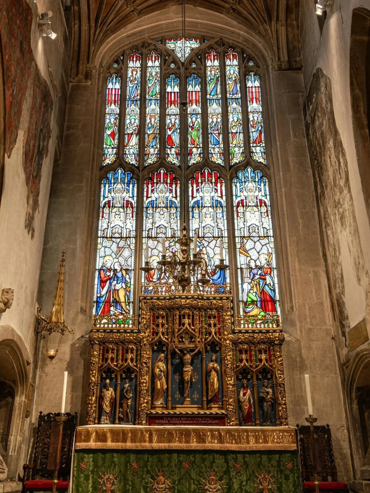 A traditional Western altar with reredos set against a large stained glass window.