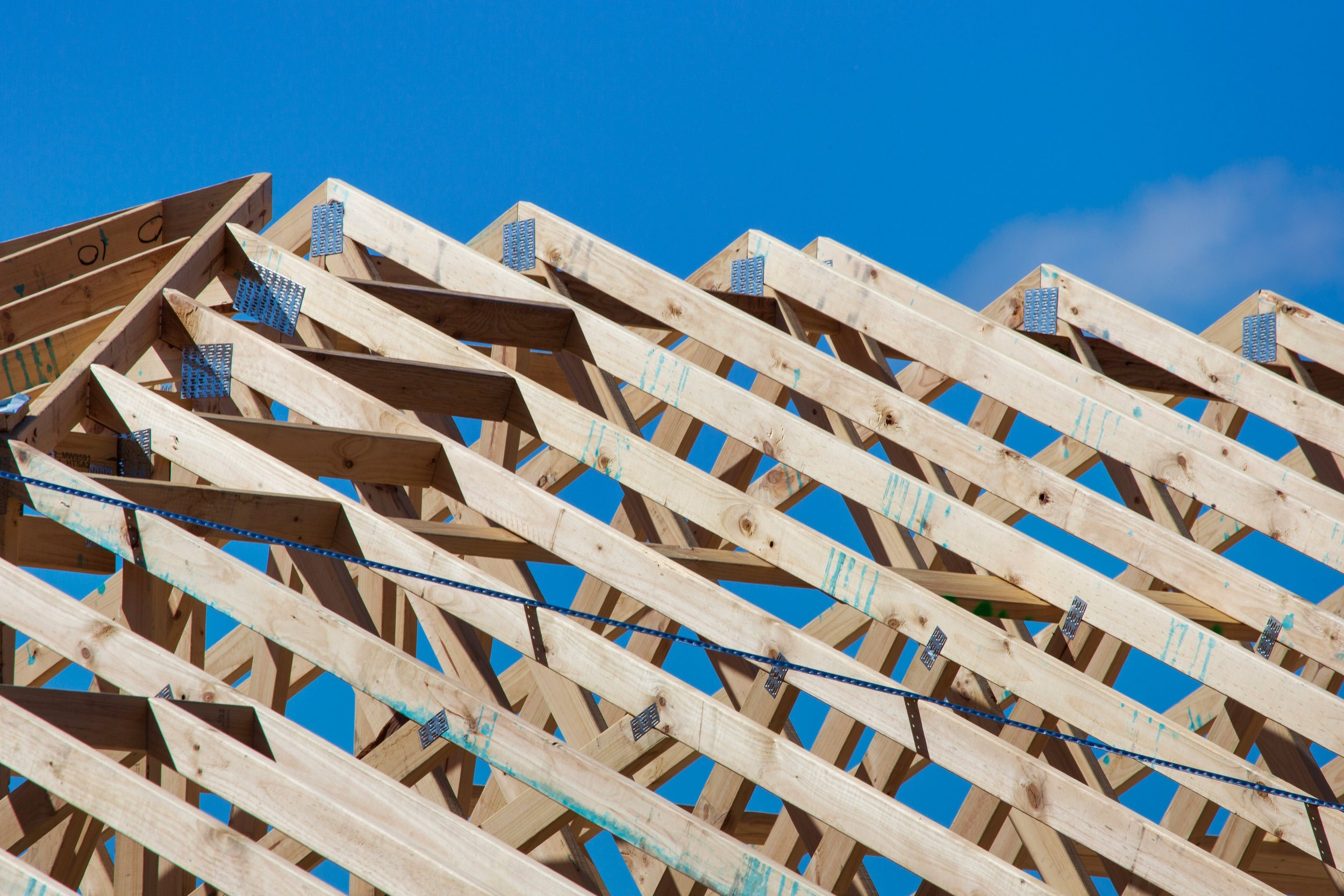 Wooden roof frame under construction against a blue sky.