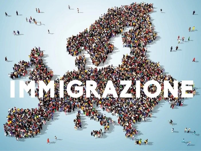 Una grande folla di persone si unisce formando la forma di una mappa dell'Europa, con la parola "IMMI GRAZIONE" sovrapposta in bianco.