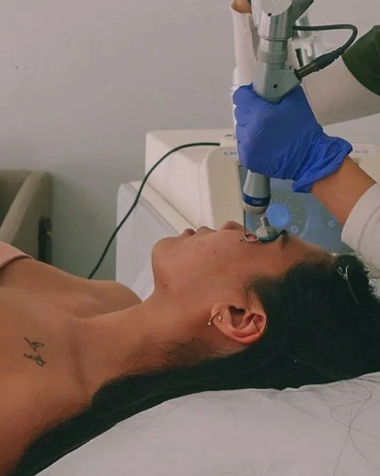 Medical professional performing laser treatment on woman's face in a clinical setting.