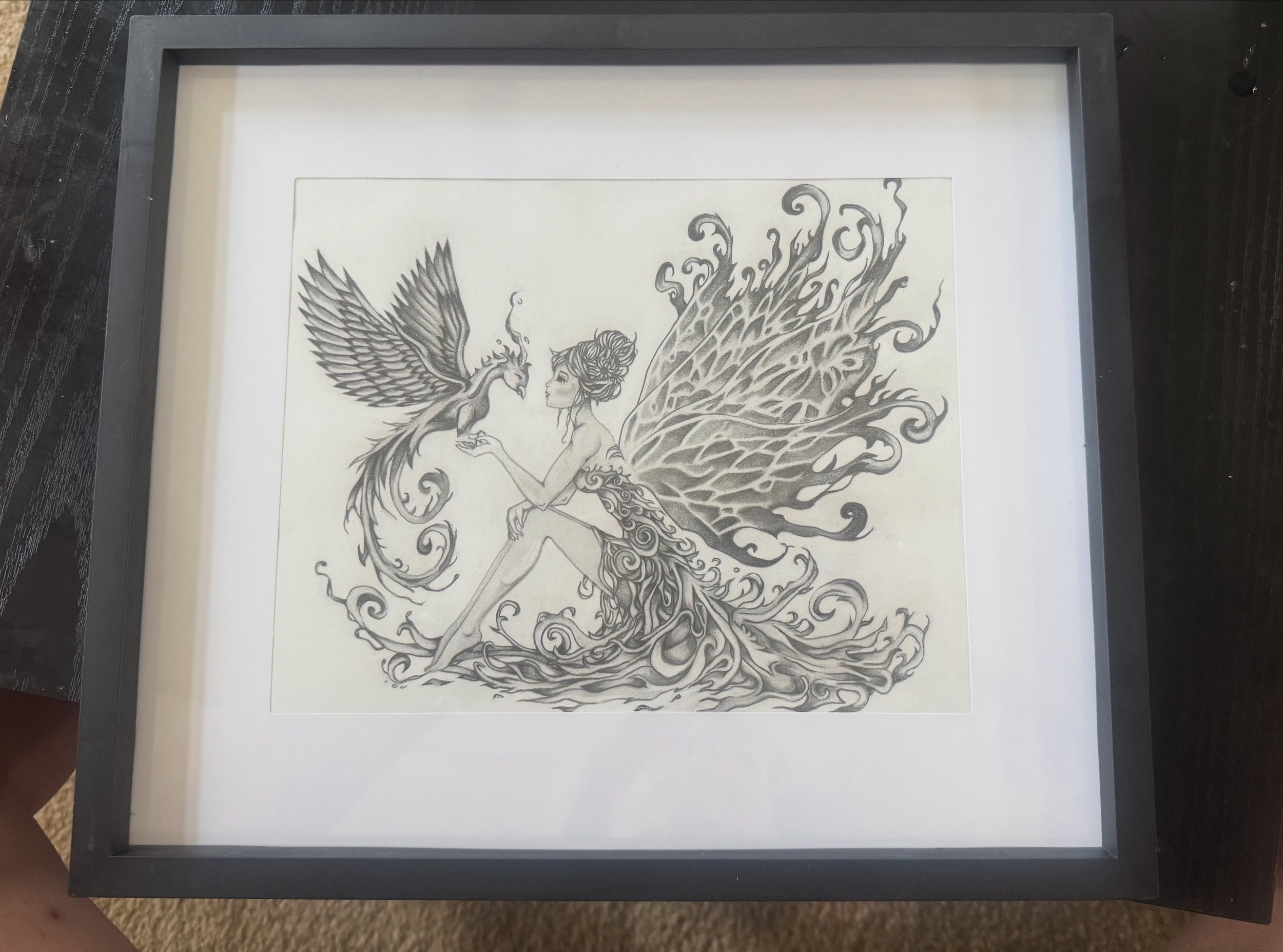 Black and white drawing of a fairy-like woman with large, intricate wings, standing and holding a bird with wings spread wide.