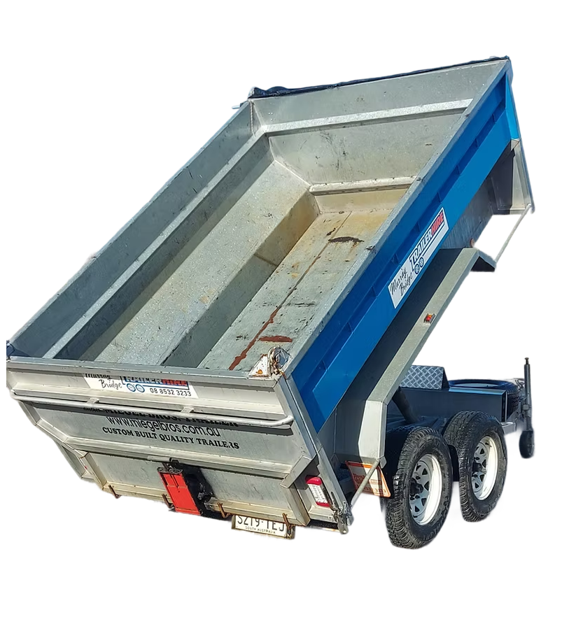 A metal dump trailer tilted upward for unloading, with dual axles and tires, painted blue with signage, on a black background.