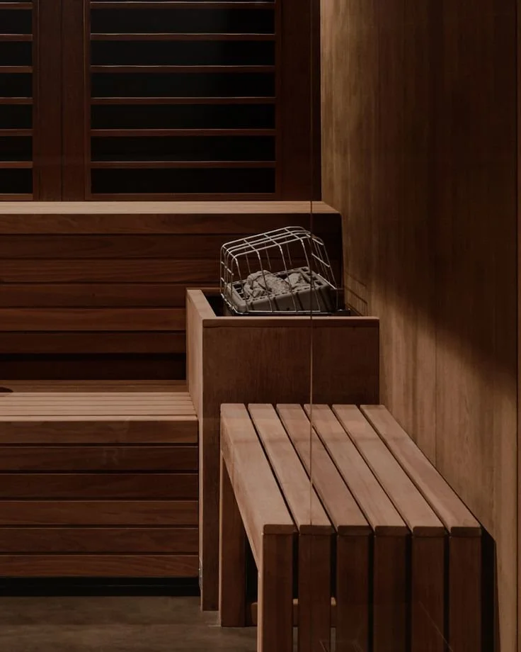 A wooden infrared sauna with a bench and a towel warmer inside.