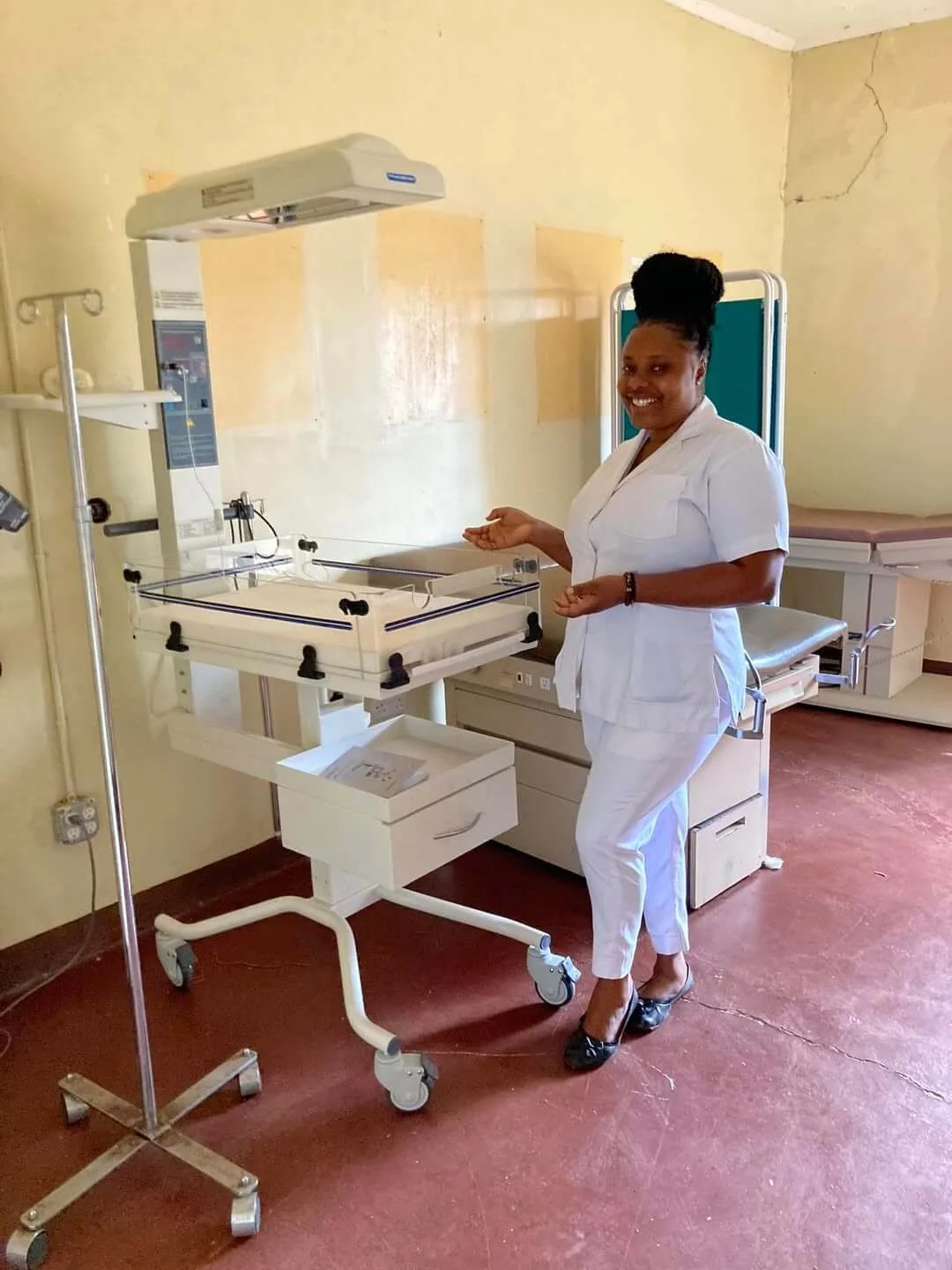 Professional nurse standing next to a medical bassinet in a hospital room.