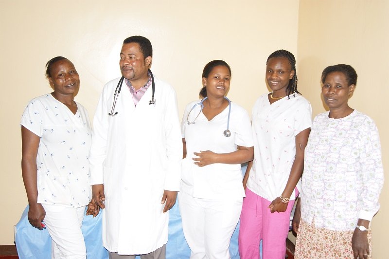 Group of five healthcare professionals, including doctors and nurses, standing together in a medical setting.