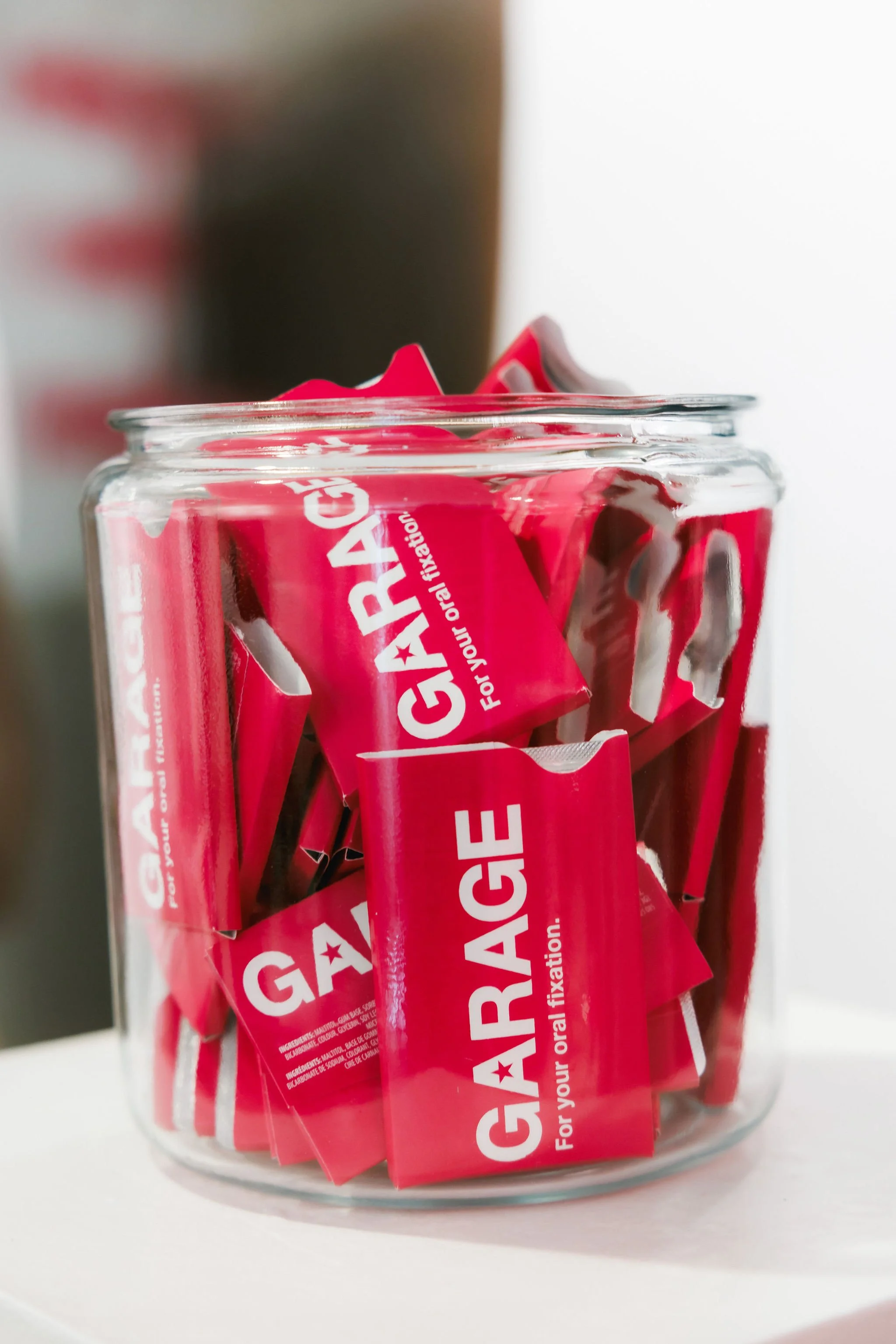 A glass jar filled with GAGARACE oral fixation candies in red packaging