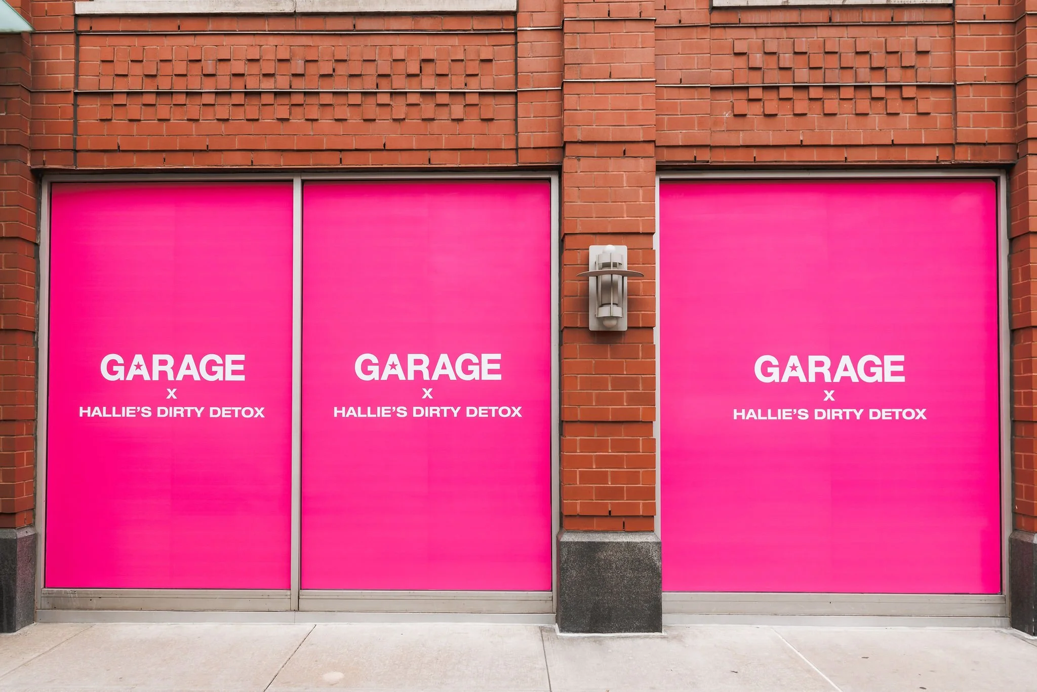 Pink storefront with two large panels displaying the words "GARAGE x HALLIE'S DIRTY DETOX" in white letters.