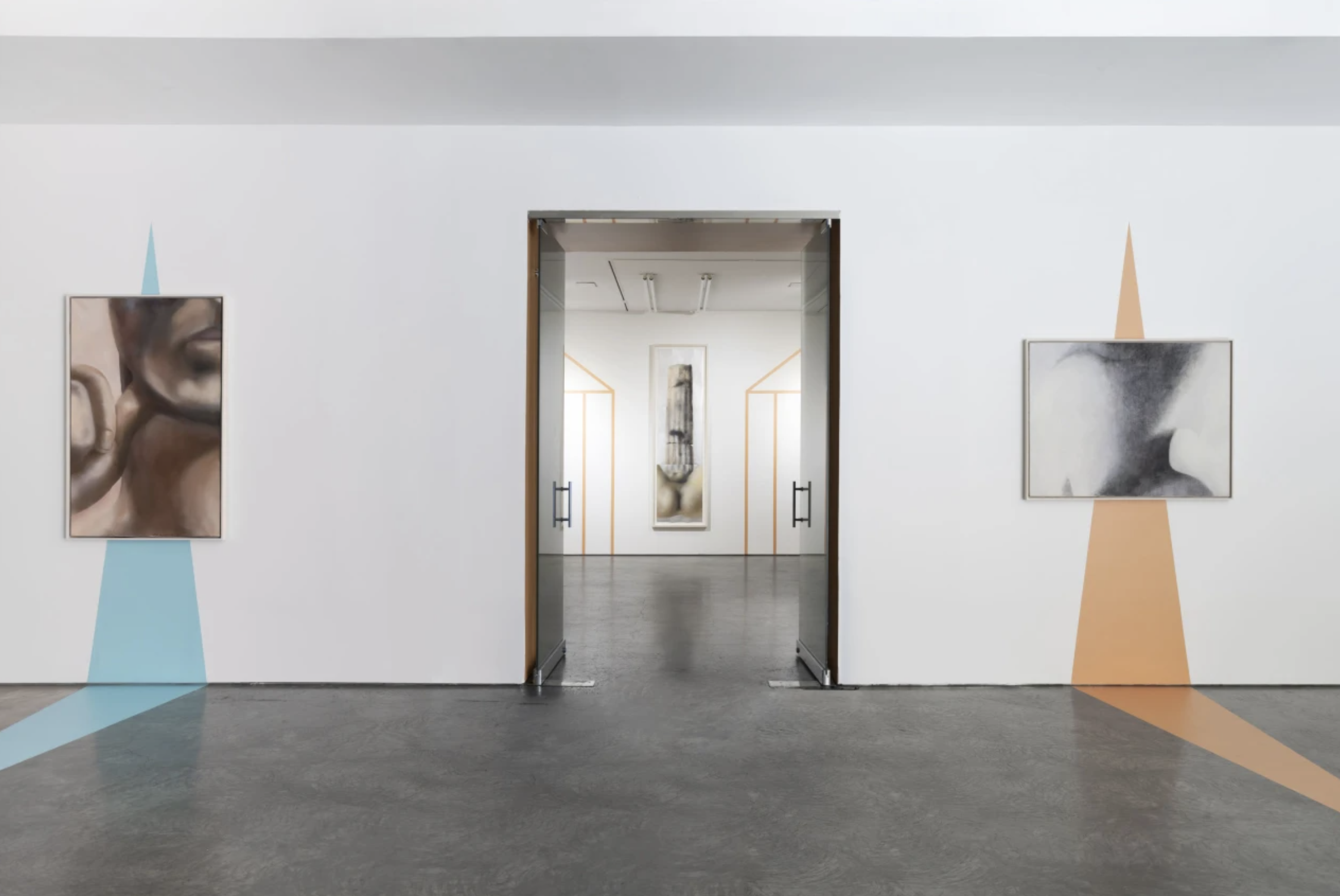 Contemporary art gallery with two paintings on white walls and geometric colored designs behind them, and an open doorway leading to a gallery space with more artworks.