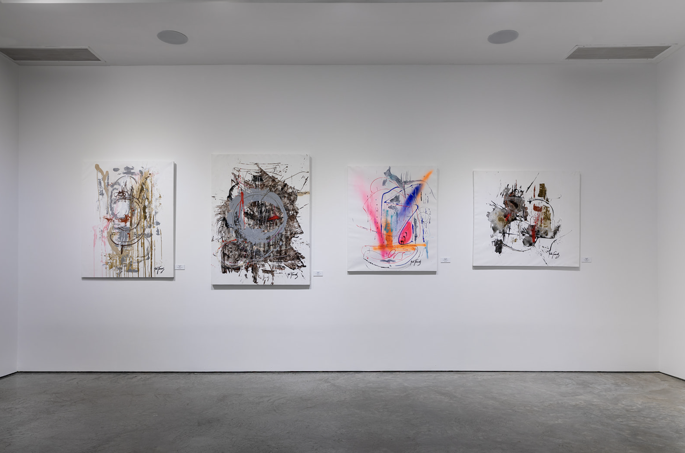 Four abstract art paintings displayed on a white gallery wall, each with unique splashes of color and expressive brushstrokes.