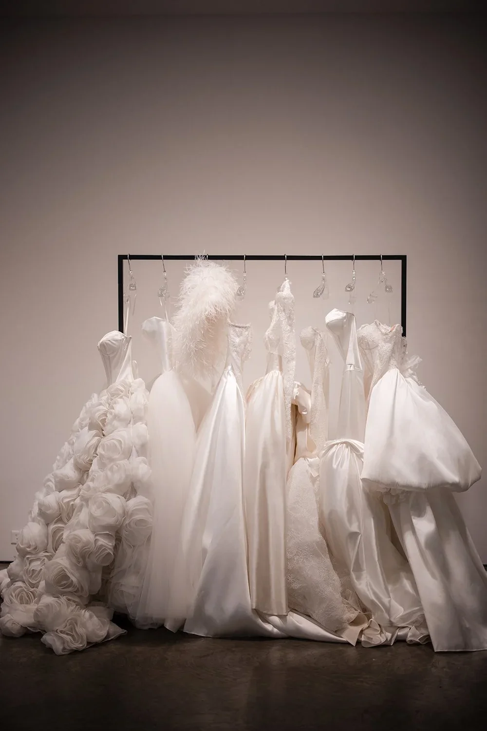 Collection of white wedding dresses hanging on a black clothing rack