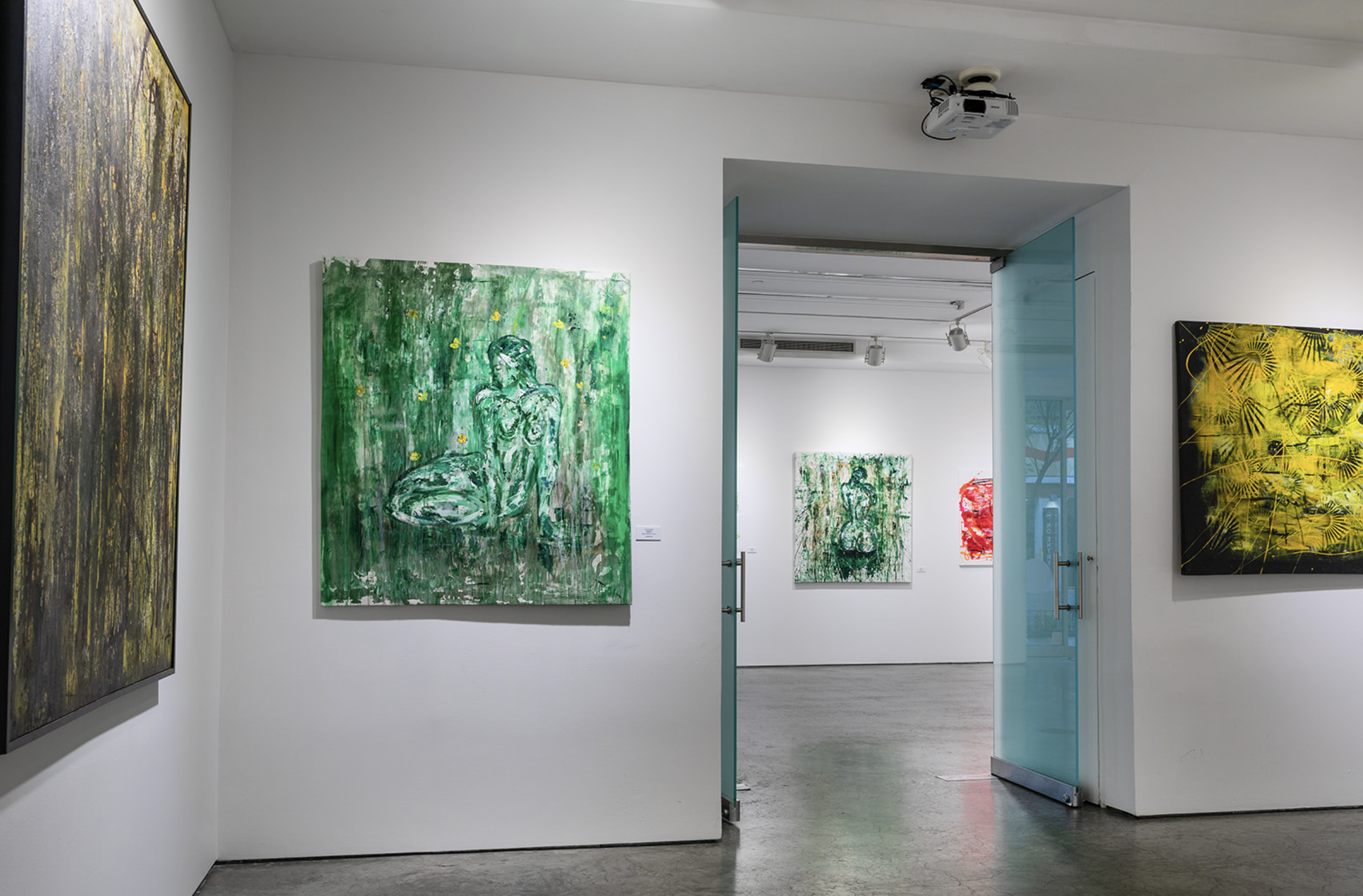 Art gallery with various paintings on white walls, including a large green painting of a seated woman and a yellow abstract piece, with a partially open glass door leading to another room.