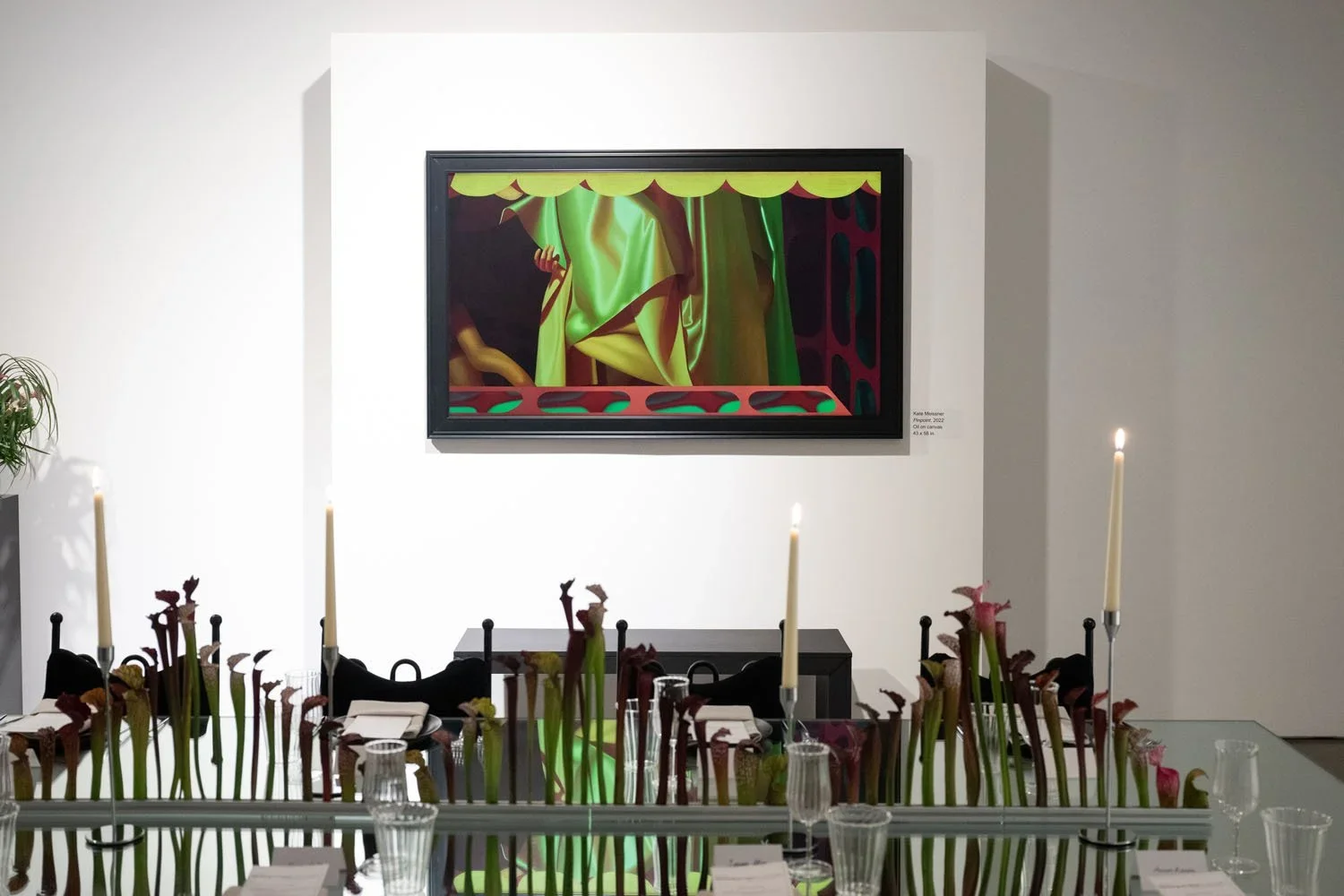 Modern dining room with a large framed abstract painting on white wall, tall candles, and floral arrangements on the table.