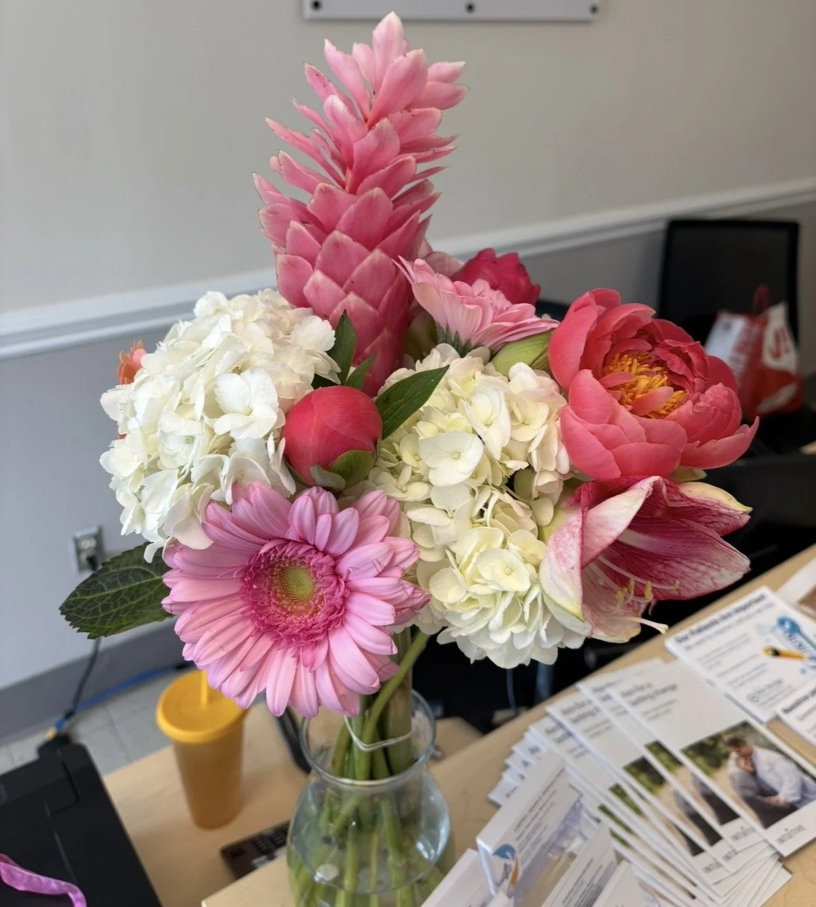 Bouquet of pink, white, and red flowers in a clear glass vase on a table.