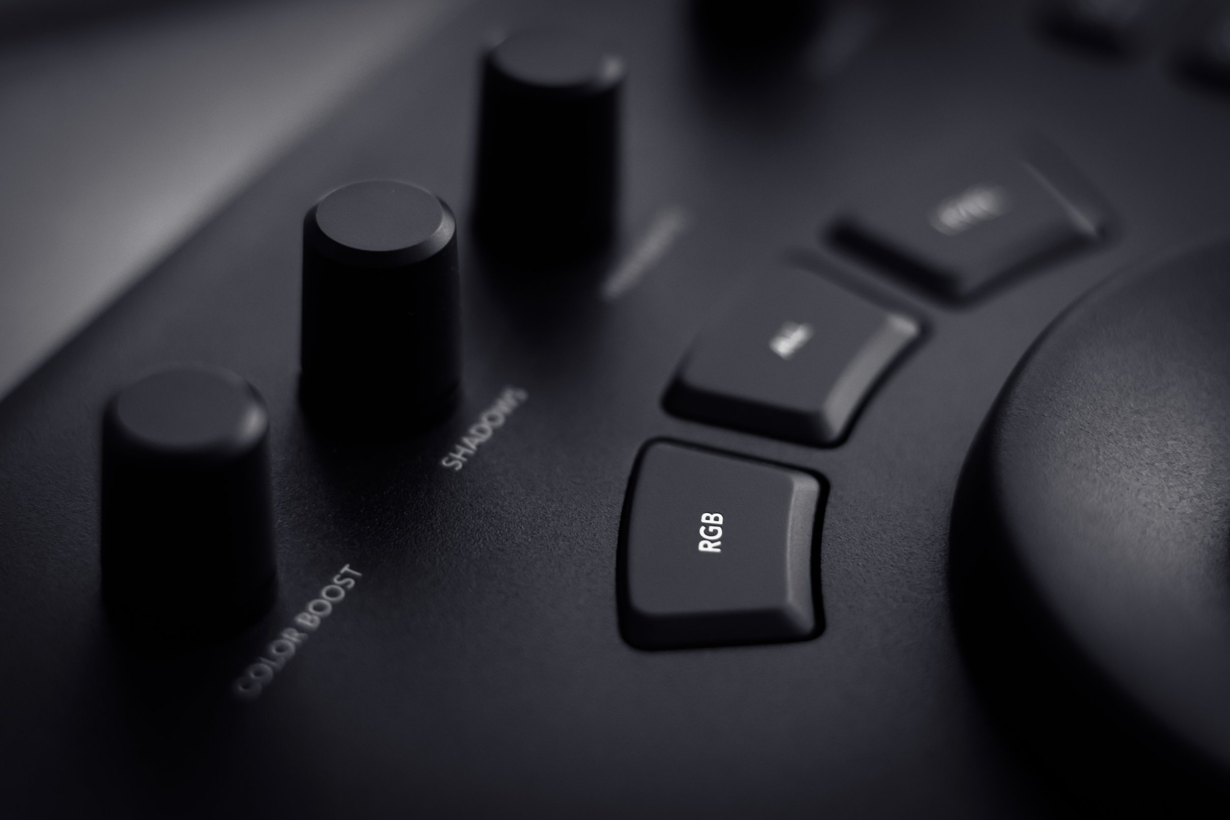 Close-up of a professional audio mixing console with black knobs and labeled buttons, including 'RGB' and 'Color Boost'.