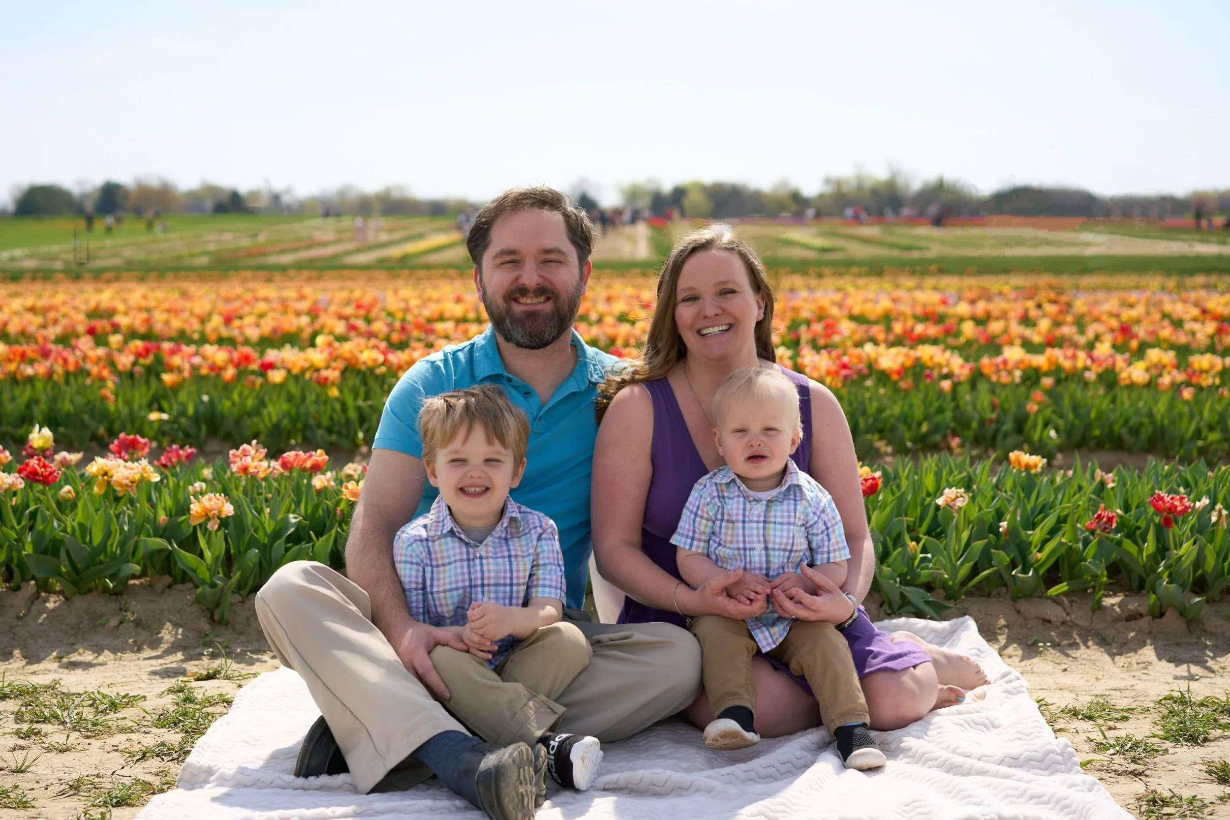 family of four sitting in a field of tulips