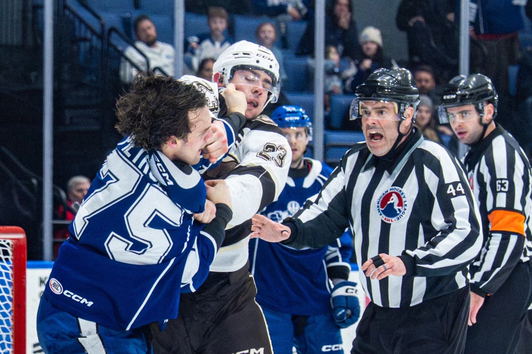 Syracuse Crunch defenseman Matteo Pietroniro (left) and Hershey Bears forward Brett Leason fight as linesman Jason Brown steps in to break it up during the third period of the Crunch's game against the Bears on Friday, March 27, 2026, at the Upstate 