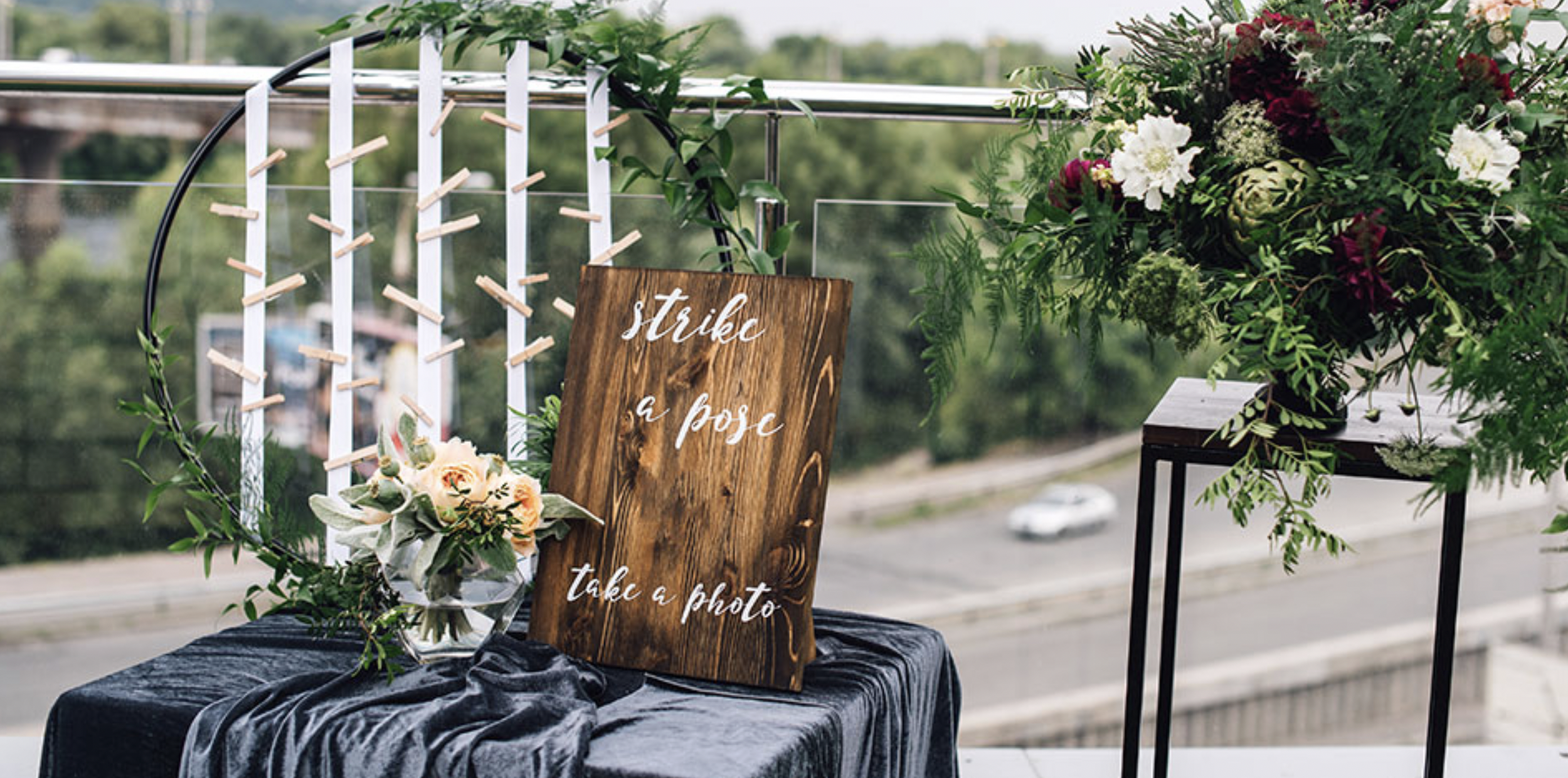 A table decorated with flowers and a sign that says 'strike a pose,' set on a balcony with a city view.