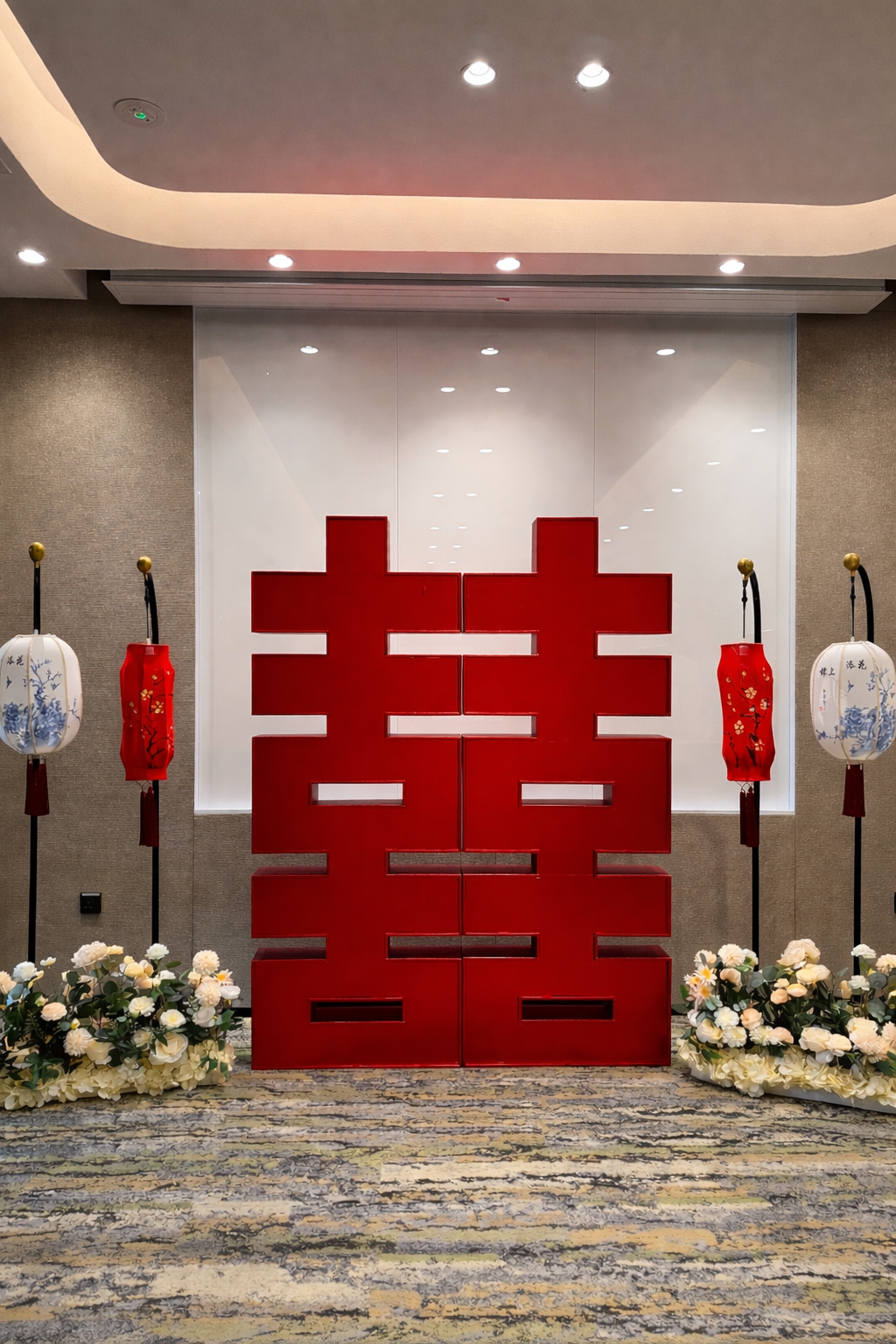 Decorative display with red Chinese character partition, white and blue lanterns, and floral arrangements in front.