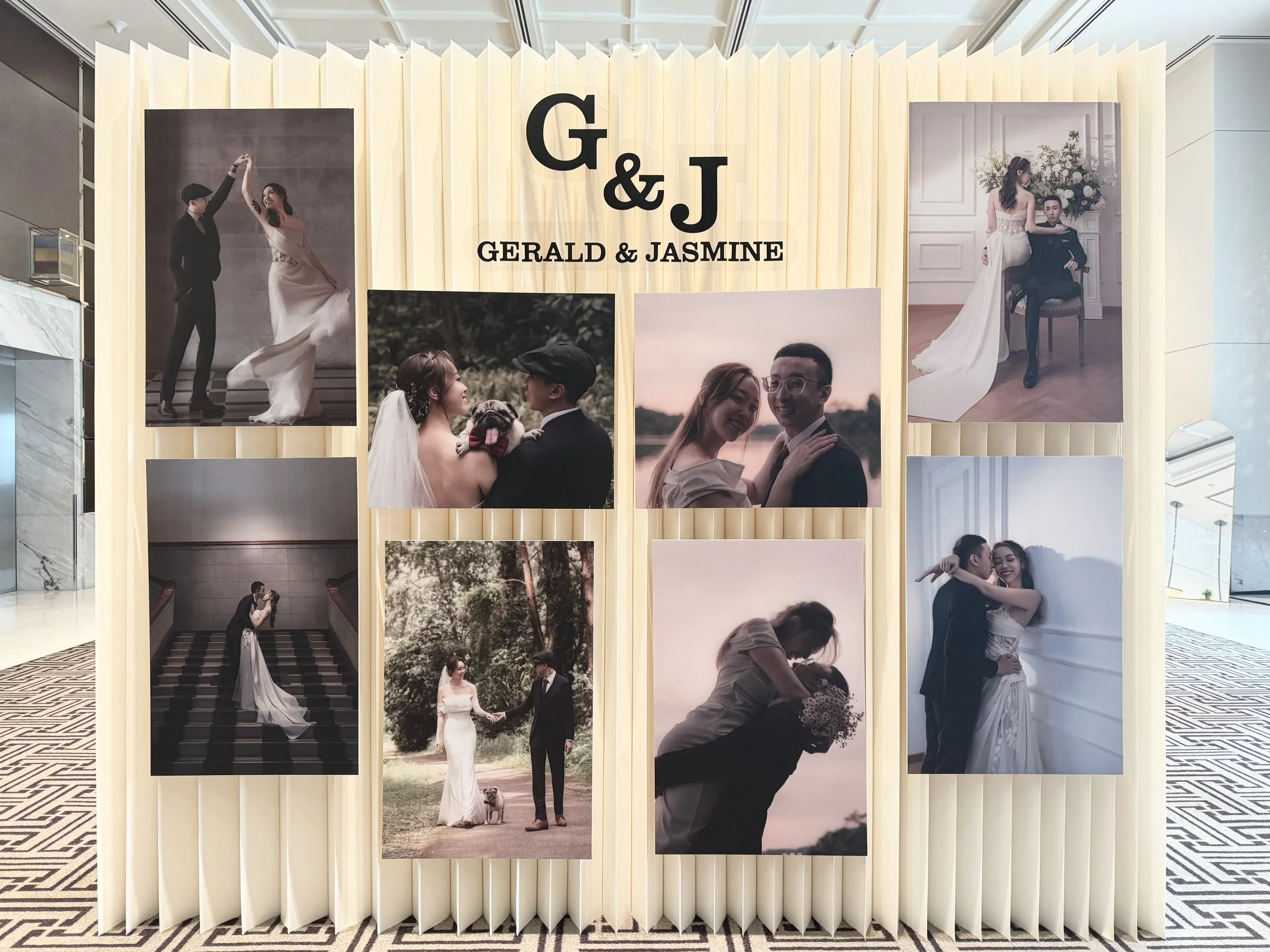 Display of wedding photographs on a decorative folding screen with cream-colored panels, featuring various poses of a bride, groom, and wedding guests at a celebration.