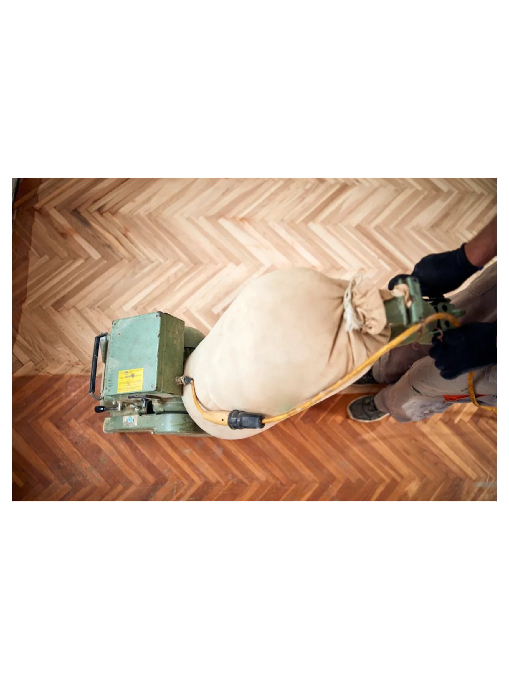 Person operating a floor sanding machine on a hardwood floor.