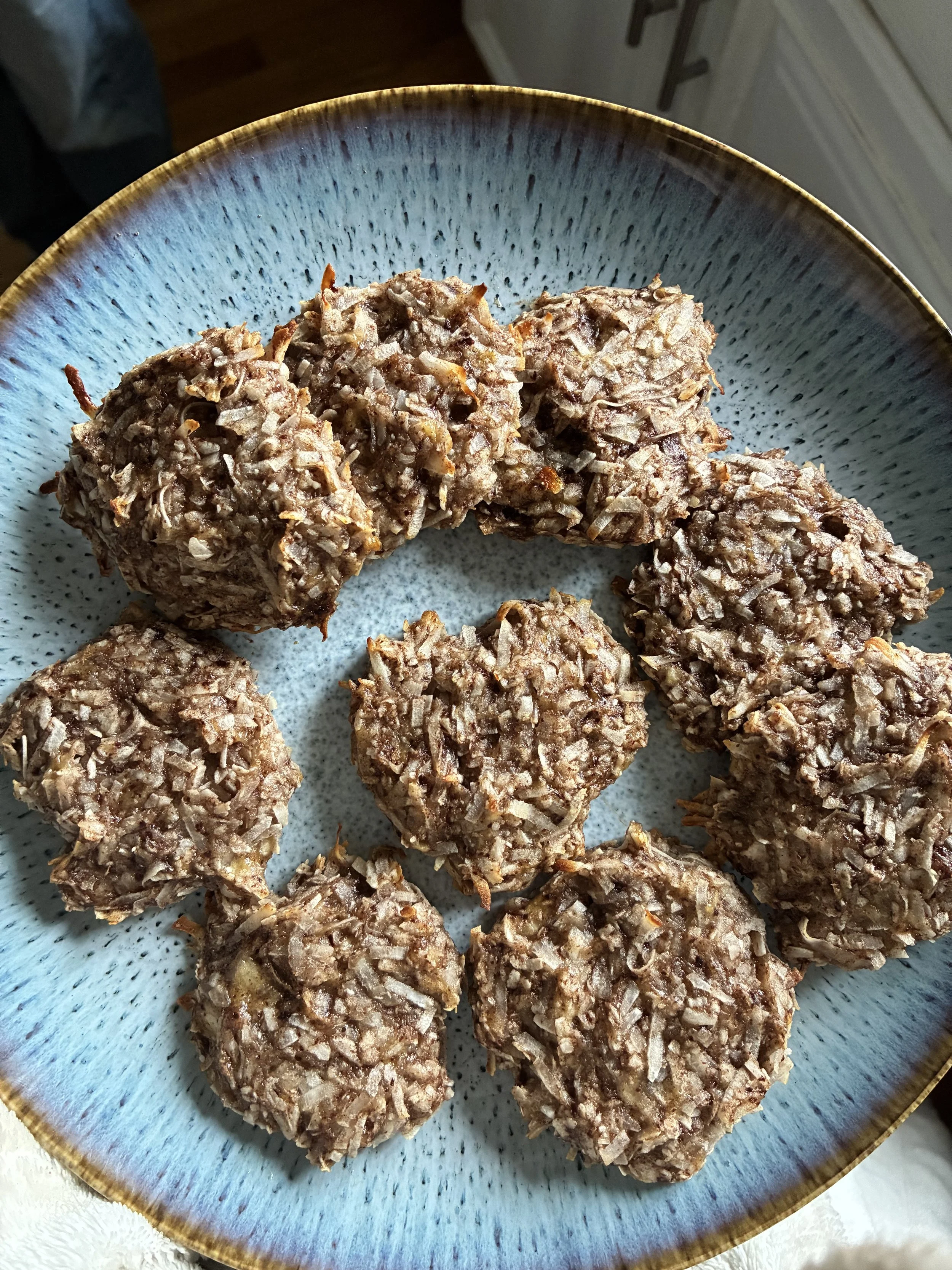 A blue ceramic plate holding eight shredded coconut-covered energy balls.