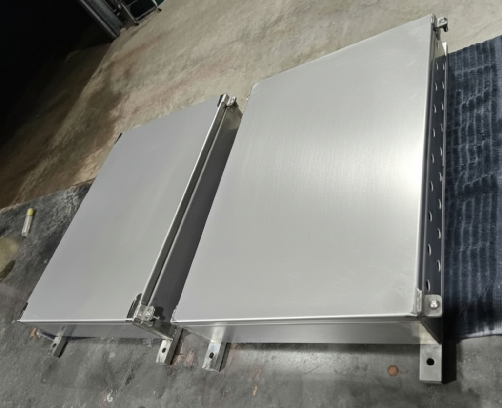 Two stainless steel kitchen ovens or cabinets placed on a work table in a workshop or garage.
