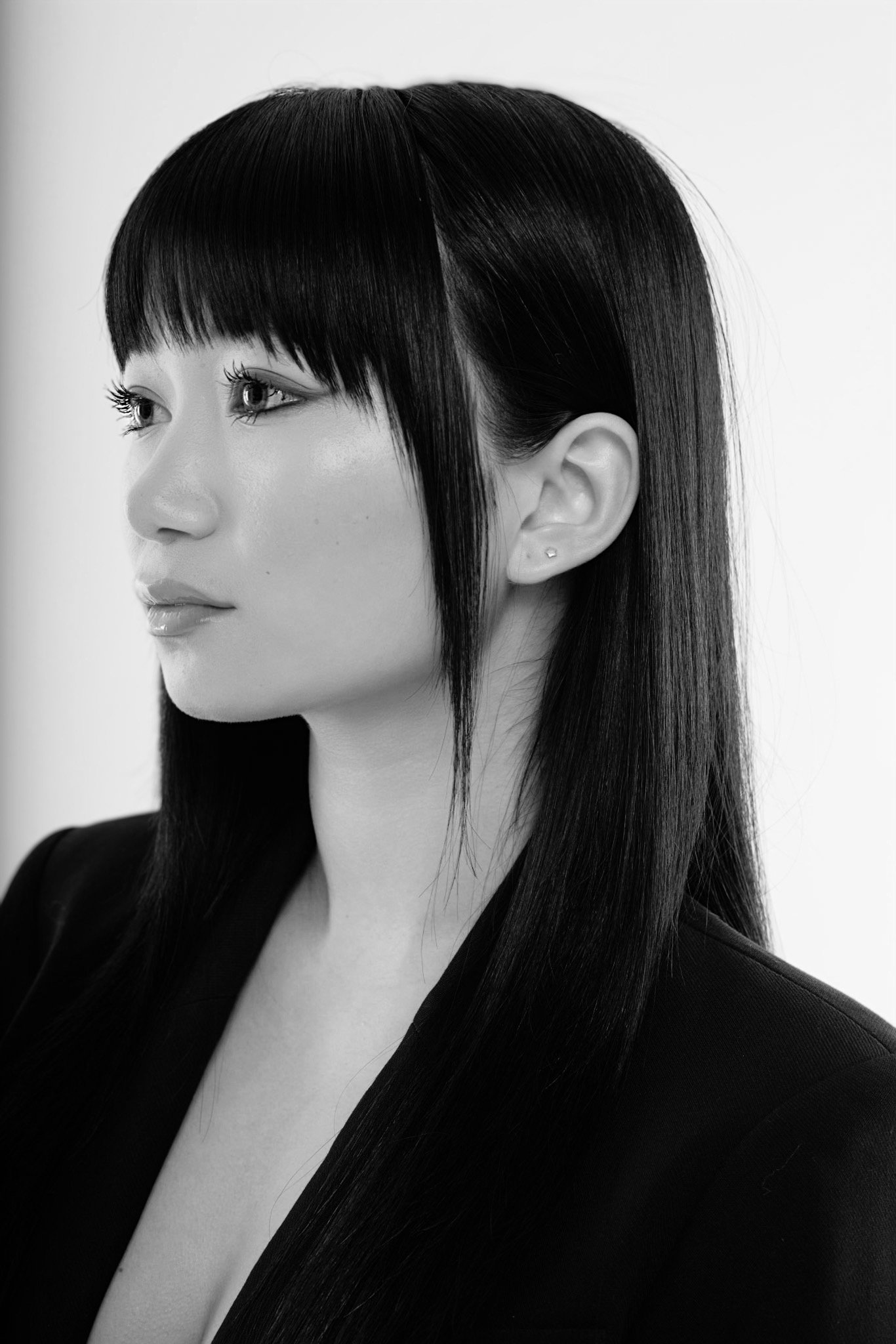Black and white portrait of a woman with straight, dark hair and bangs, wearing a dark blazer.